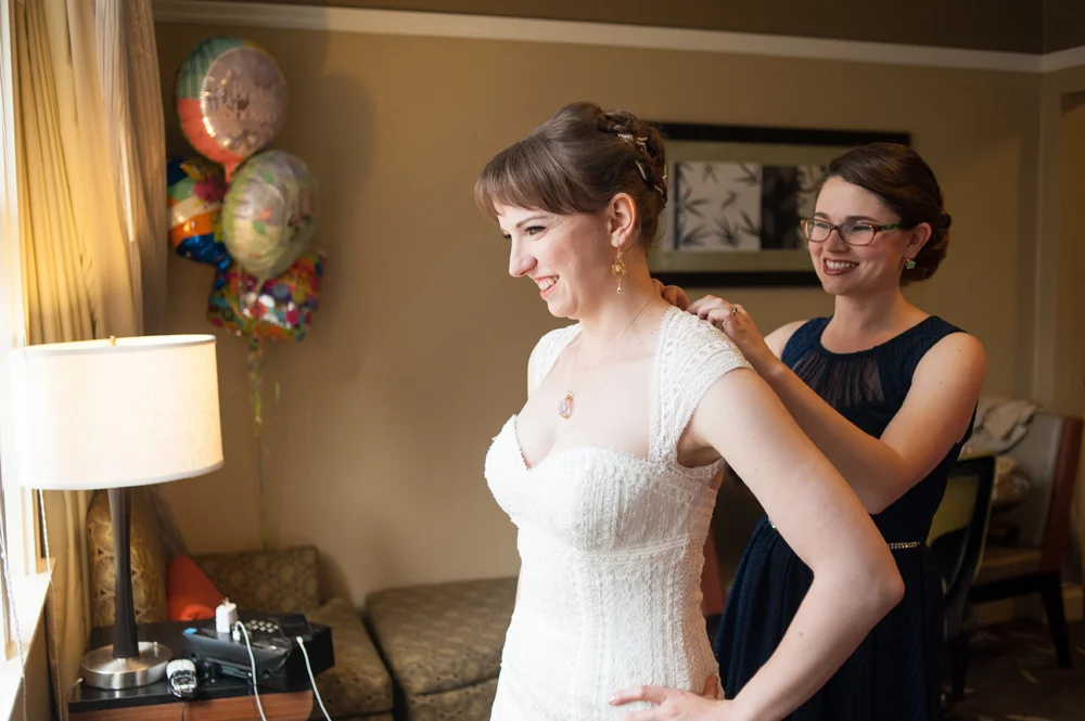 Maid of honor helping bride with wedding dress in San Francisco
