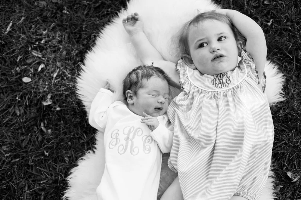 Big sister and little baby brother laying on grass
