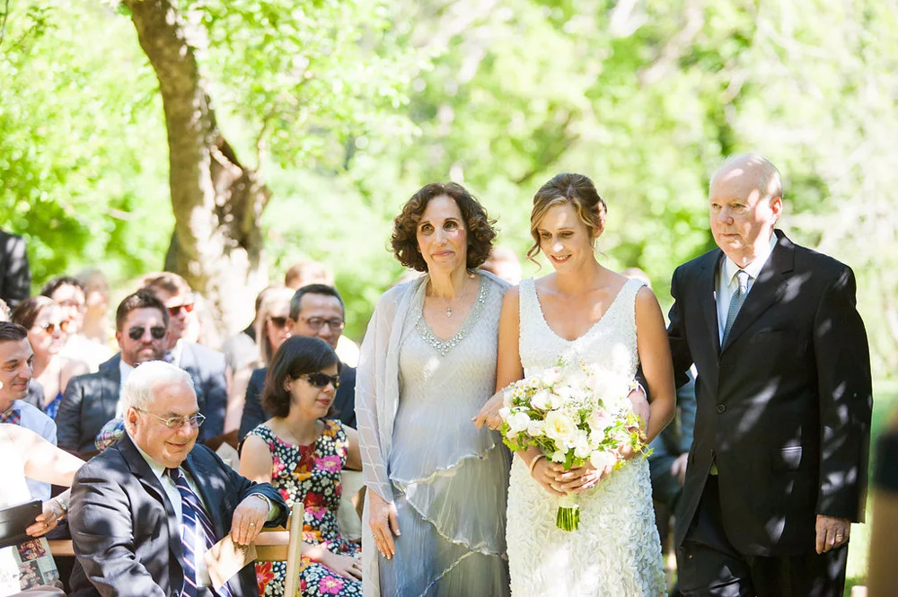 Bride walking down the aisle with parents during ceremony at Dawn Ranch