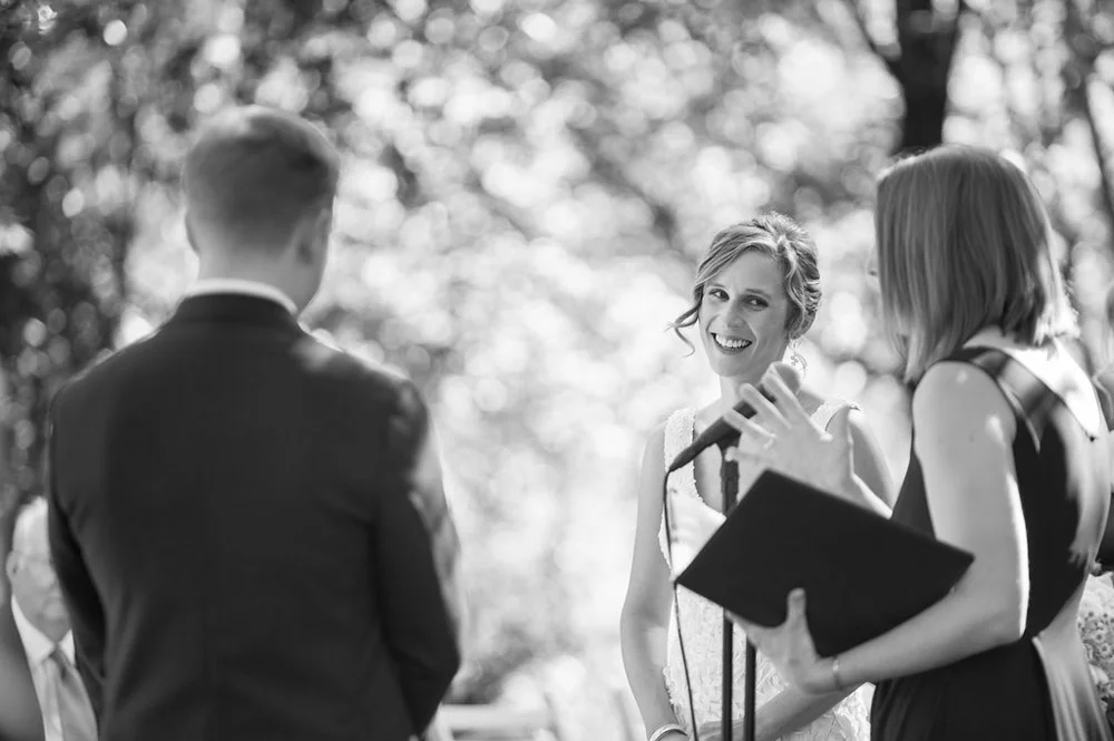 Black and white candid photo of smiling bride during wedding ceremony
