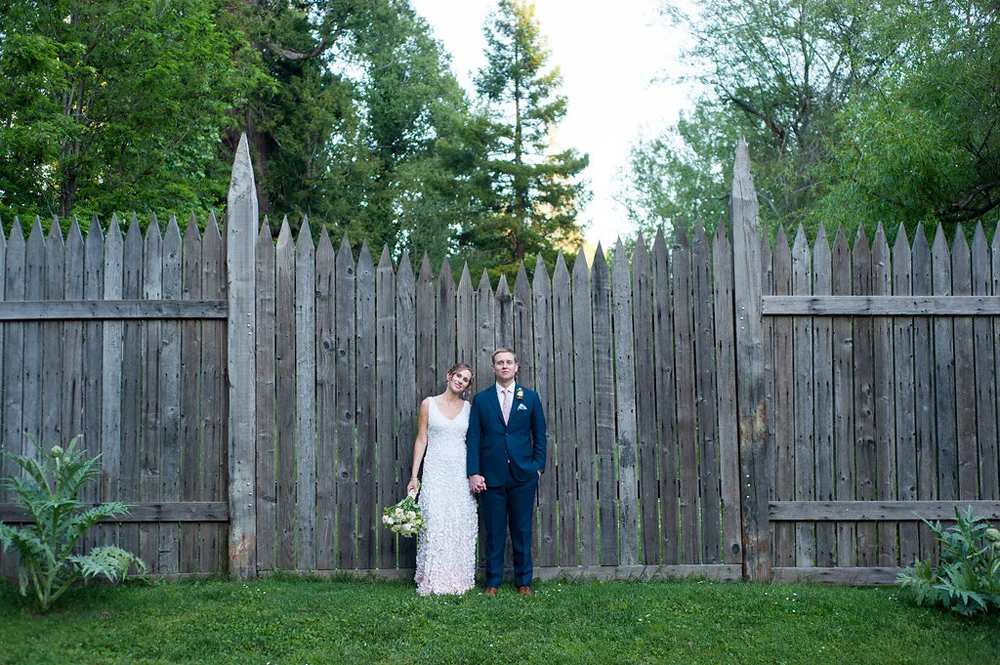 Portrait of bride and groom in front of rustic wood mideviel wall