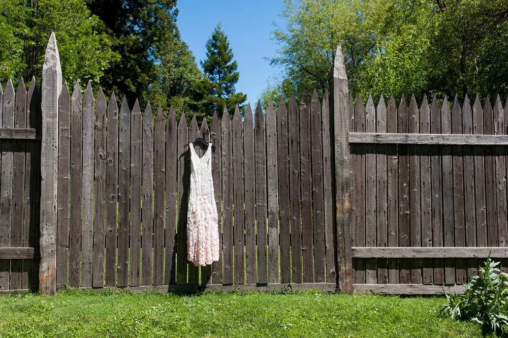 Wedding dress hanging on wooden fence at Dawn Ranch