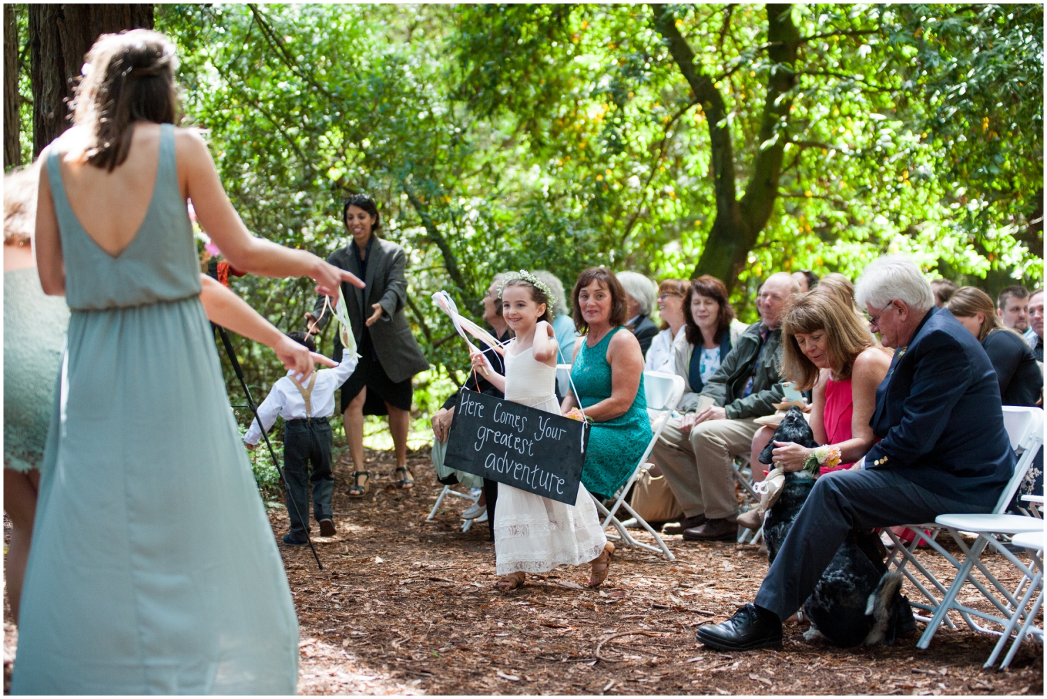 Flower girl walking up aisle at wedding in redwood grove