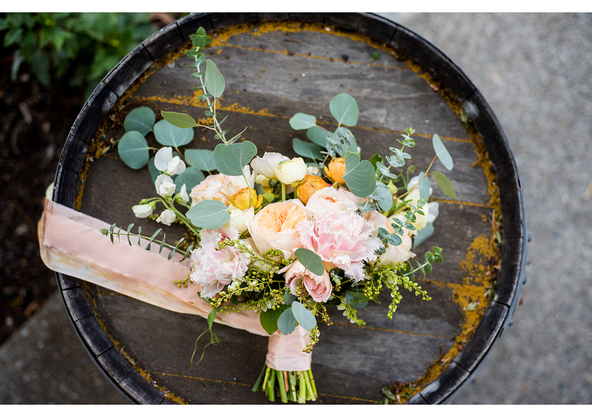 Bride's bouquet resting on top of wine barrel