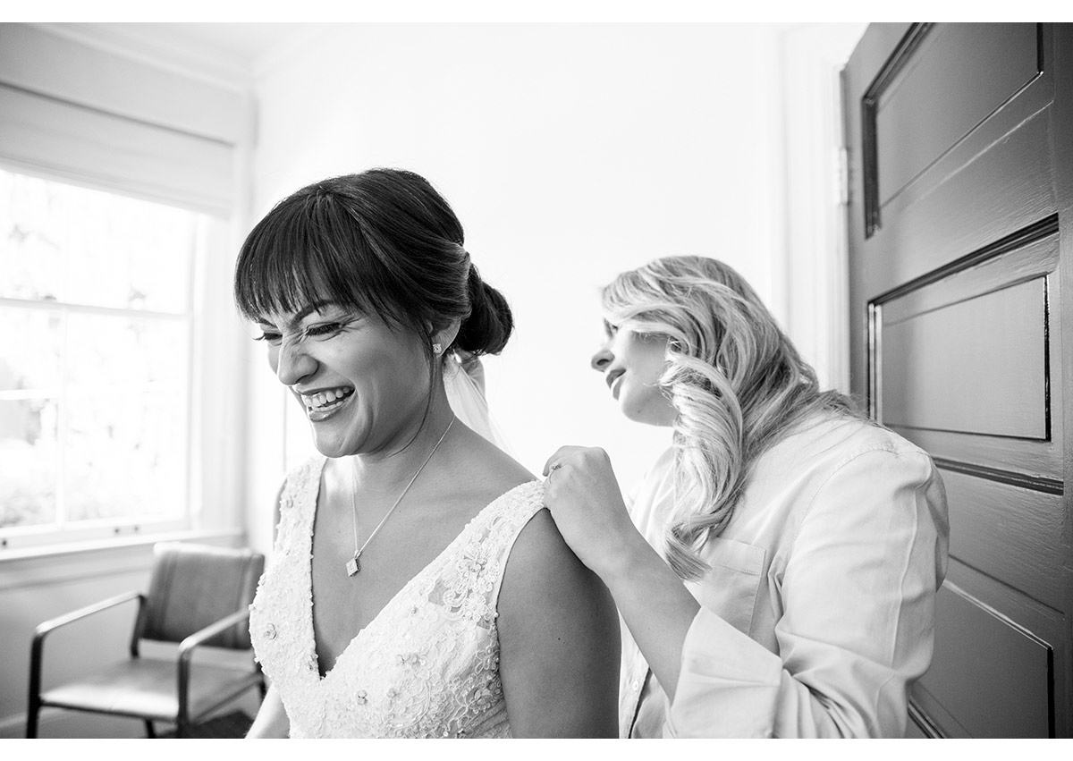 Black and White of Bride getting into wedding dress