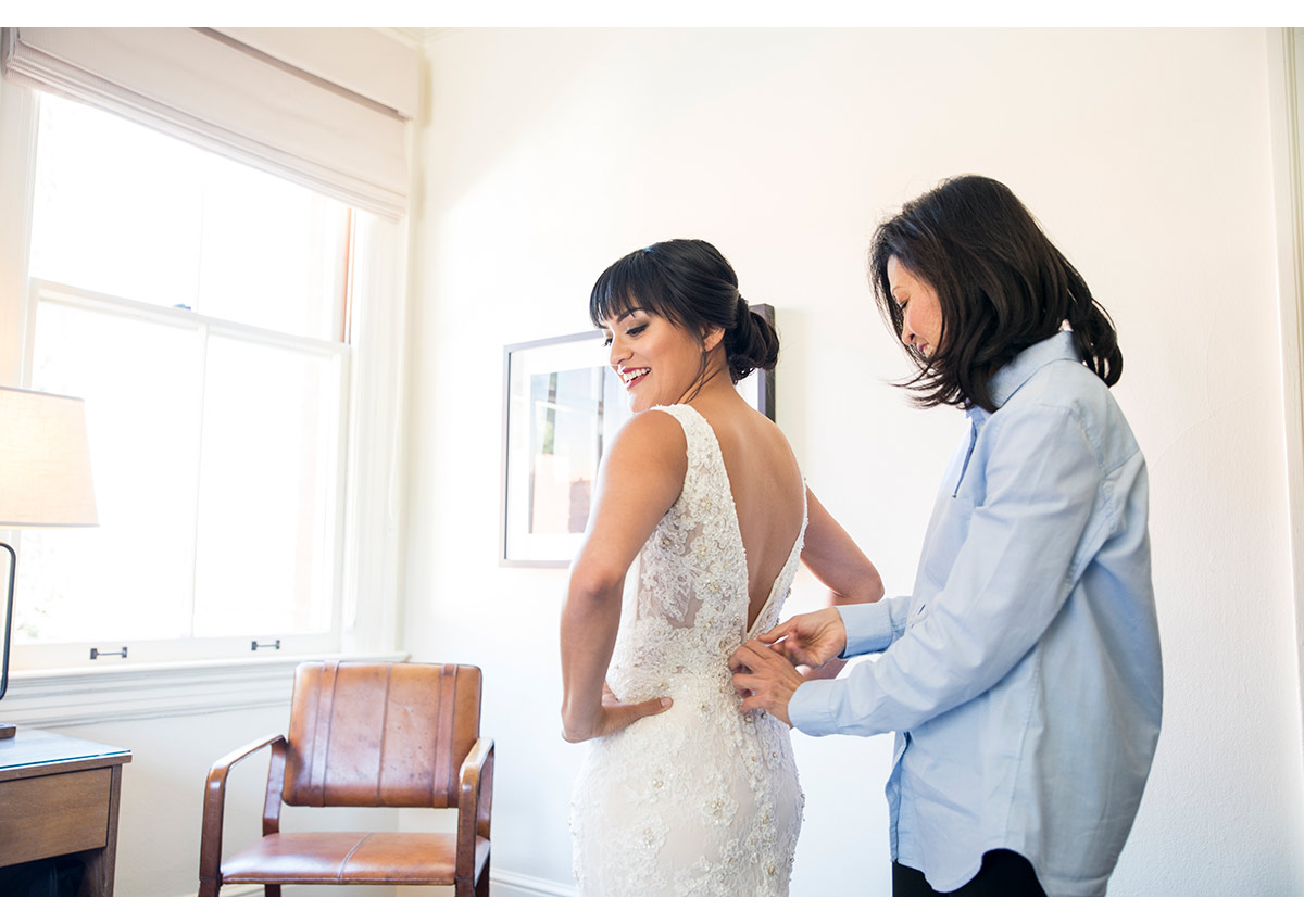 Mother of bride helping bride into wedding dress at Inn at the Presidio
