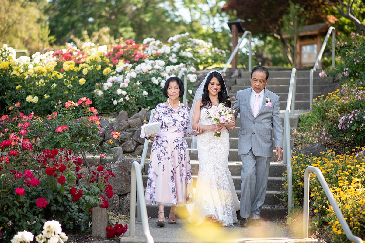 Bride walking down stairs with parents in Walnut Creek