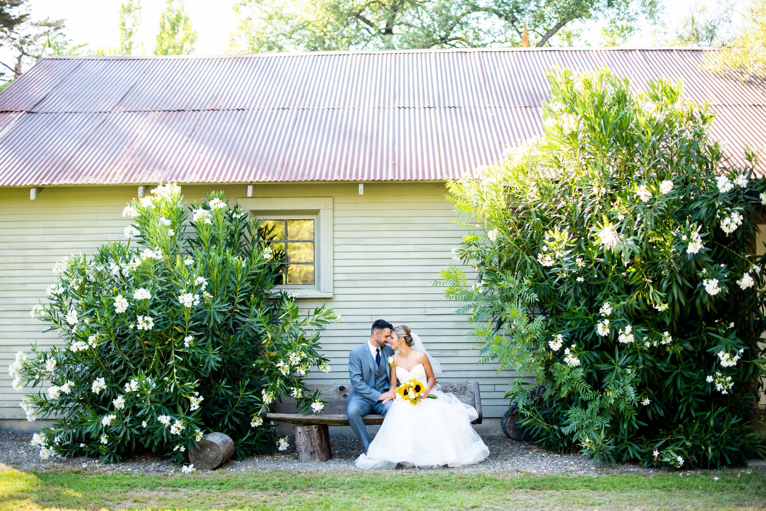 Bride and Groom on bench in front of barn 