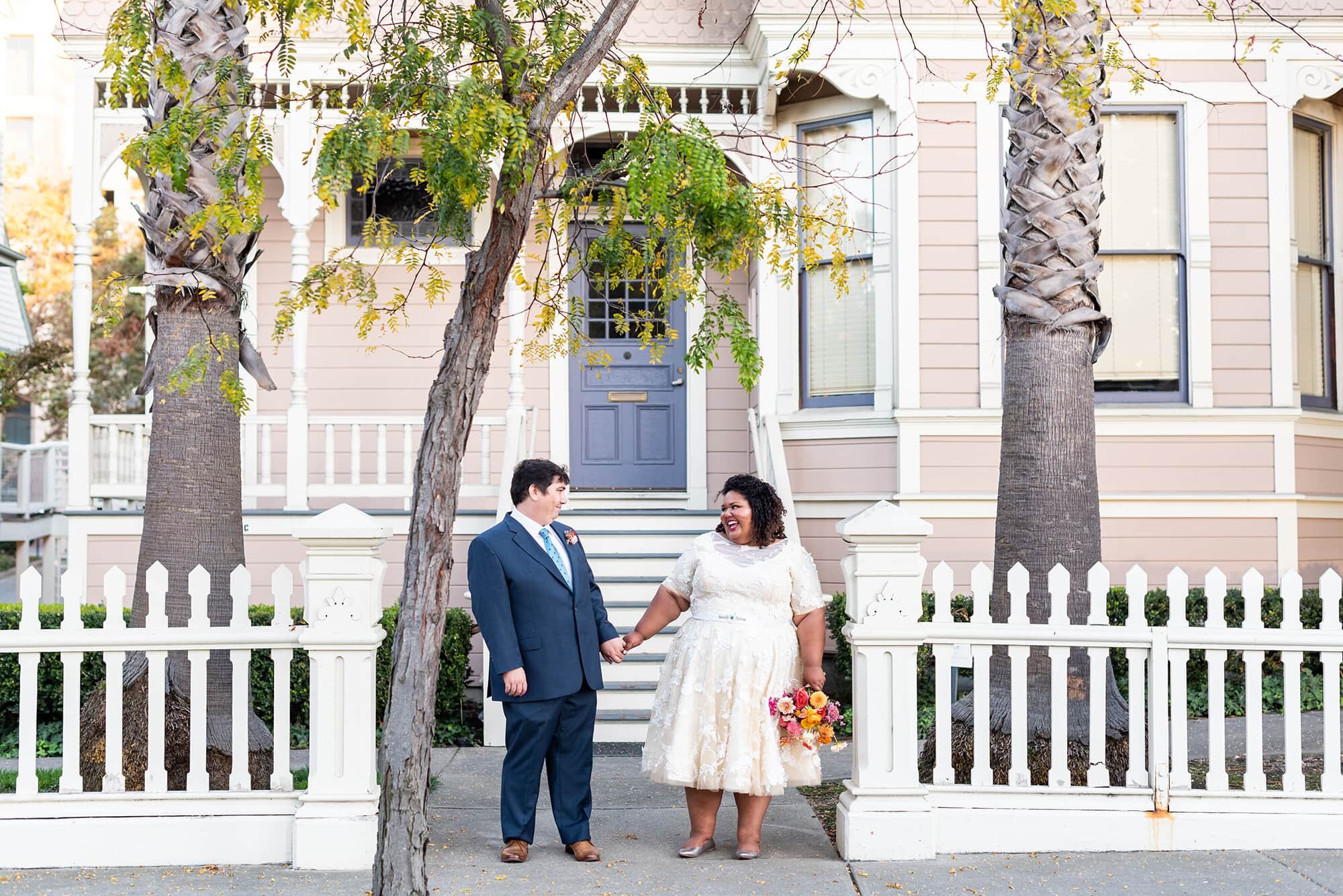 Couple standing in front of house with white picket fence