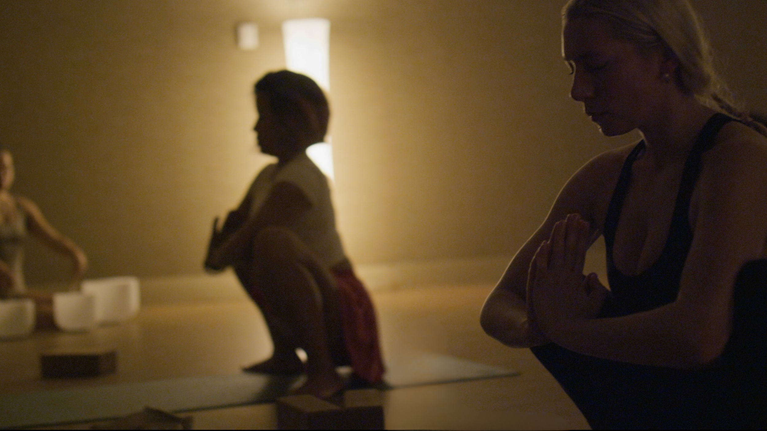 Yoga student in triangle post in the foreground with many students practicing same pose in the background