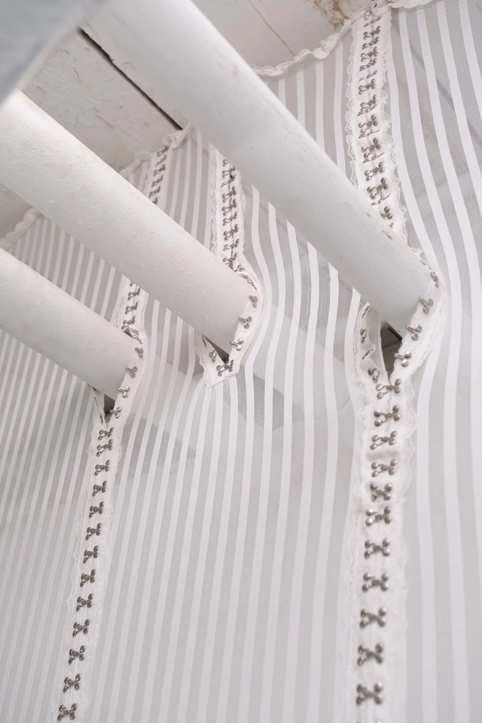   Bodice for Lyonya, Fedya, Katya and Vinny                                       2025. Site-specific installation with spandex mesh, linen, shelves, kettle bells, door draft stoppers, trim, linen thread, fabric polymer, ceramic, zip ties, oil paint,