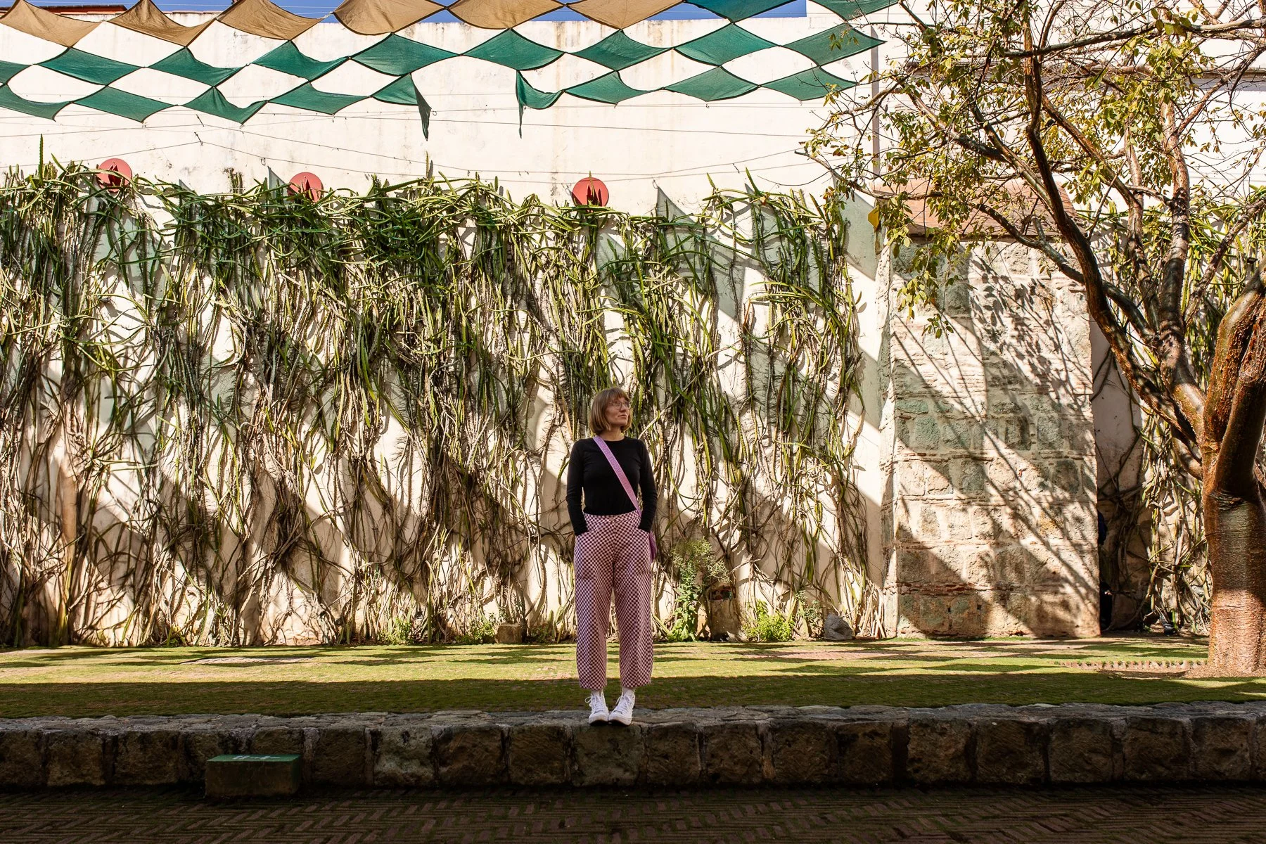 Woman standing in courtyard under canopy and shadows