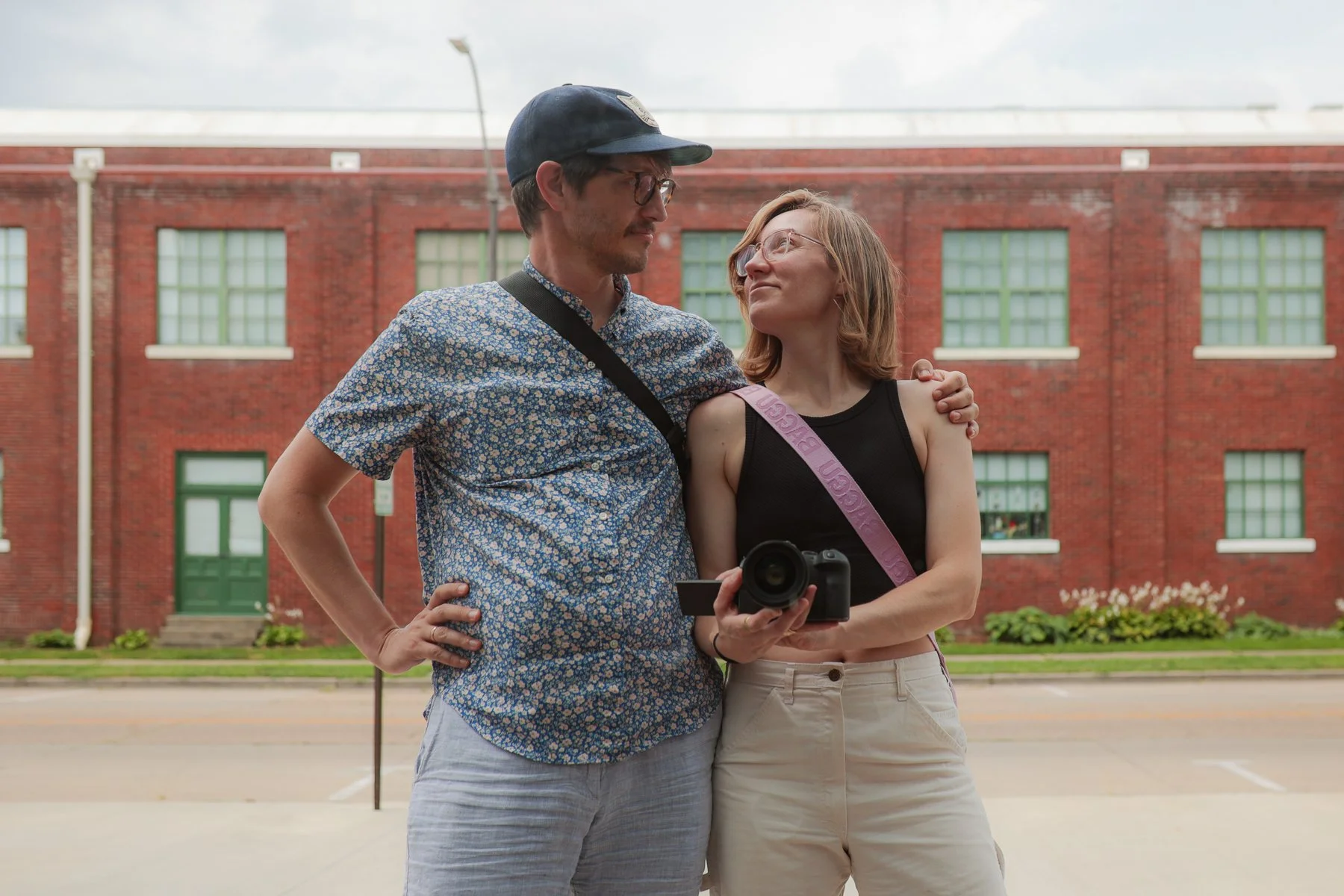 Husband and wife looking at each other while taking photo in the reflection of a building