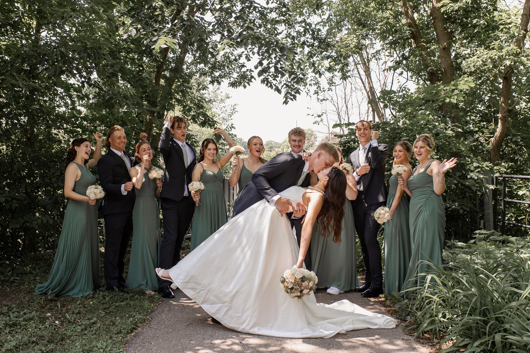wedding party cheering as bride and groom kiss