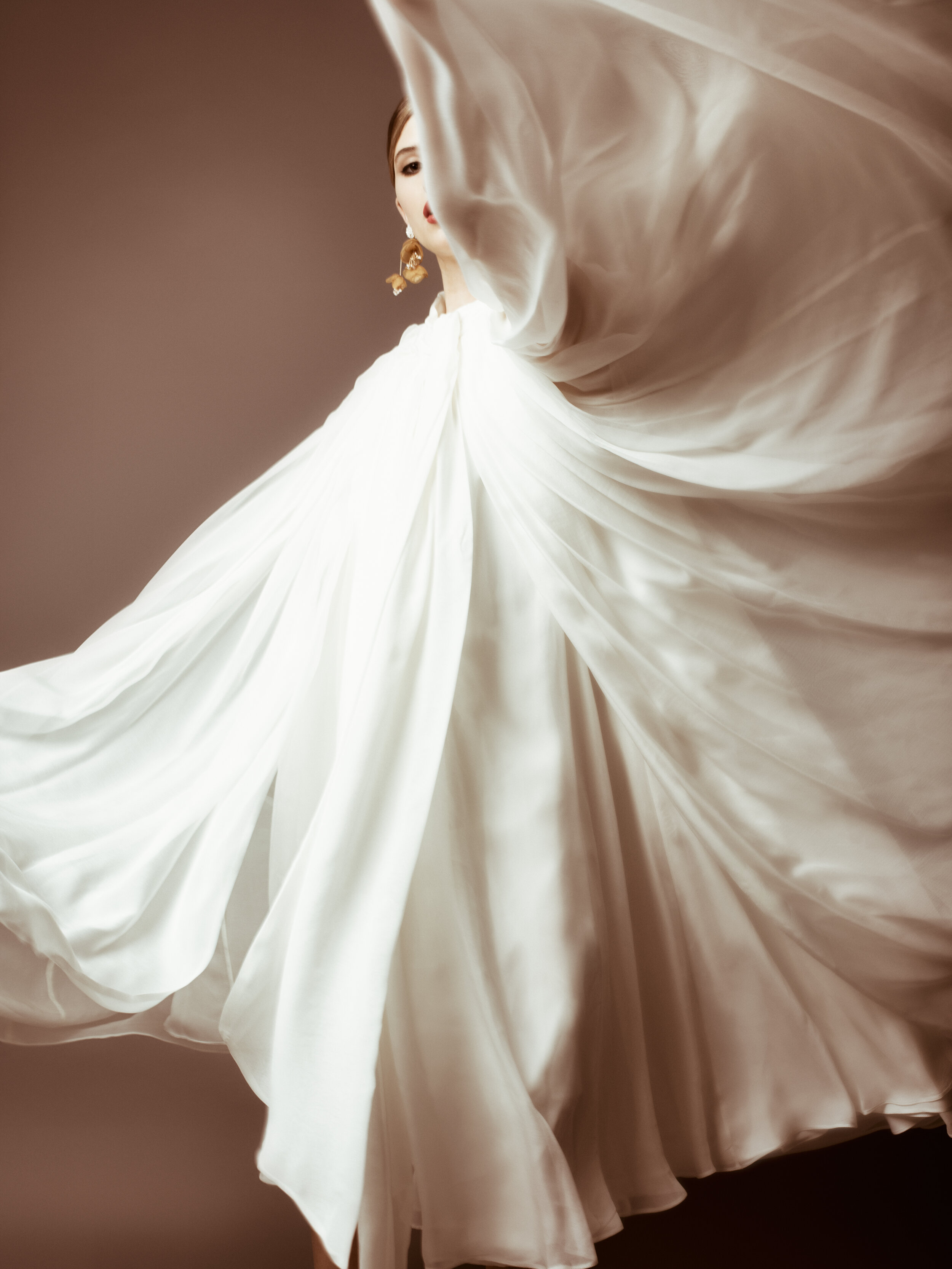  New York editorial styling featuring woman spinning in white chiffon dress with soft, artistic motion 