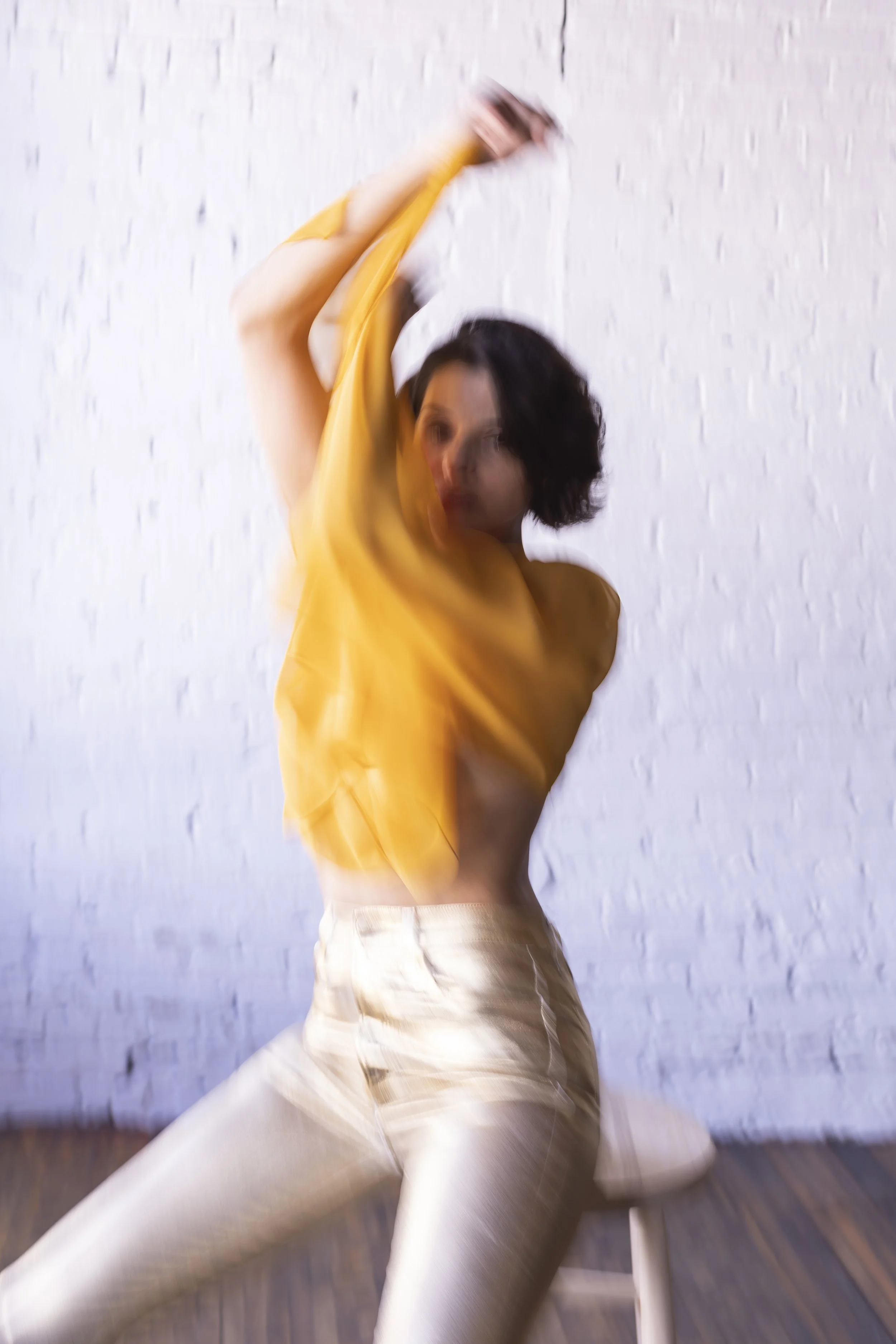  New York editorial styling by fashion consultant featuring alternate view of model in sheer orange top and gold pants with fabric draped over face 