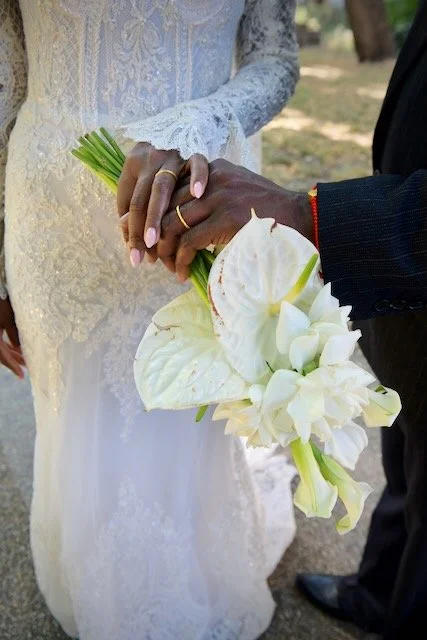 Close-up of the bride and groom holding hands with their wedding rings and white bridal bouquet during a London wedding.