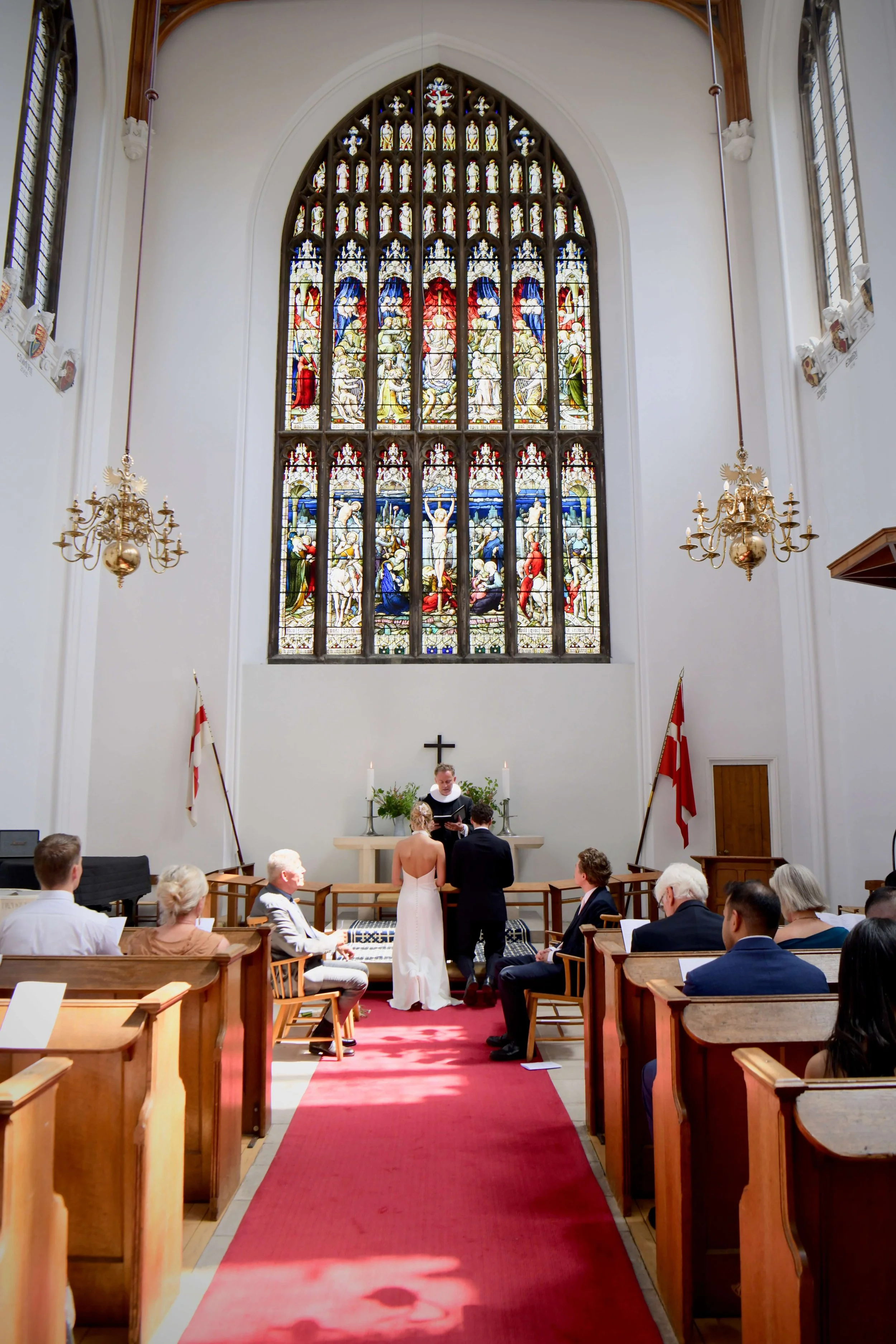 Elegant church wedding ceremony in London featuring a couple exchanging vows beneath stunning stained-glass windows and timeless historic architecture. Perfect inspiration for classic and luxury wedding photography.