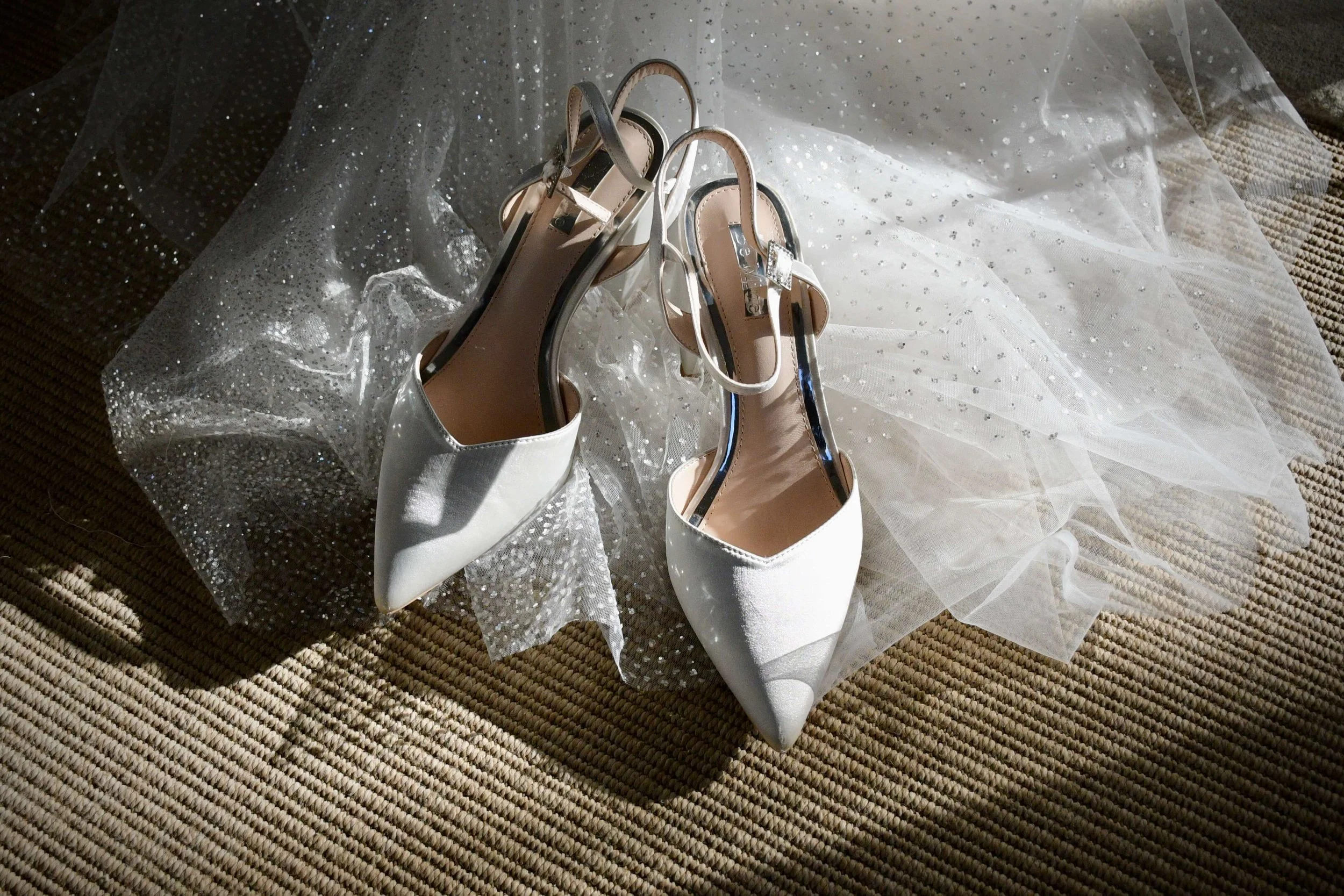 Romantic bridal accessories detail shot featuring white wedding shoes on glittered veil – fine art wedding photography.