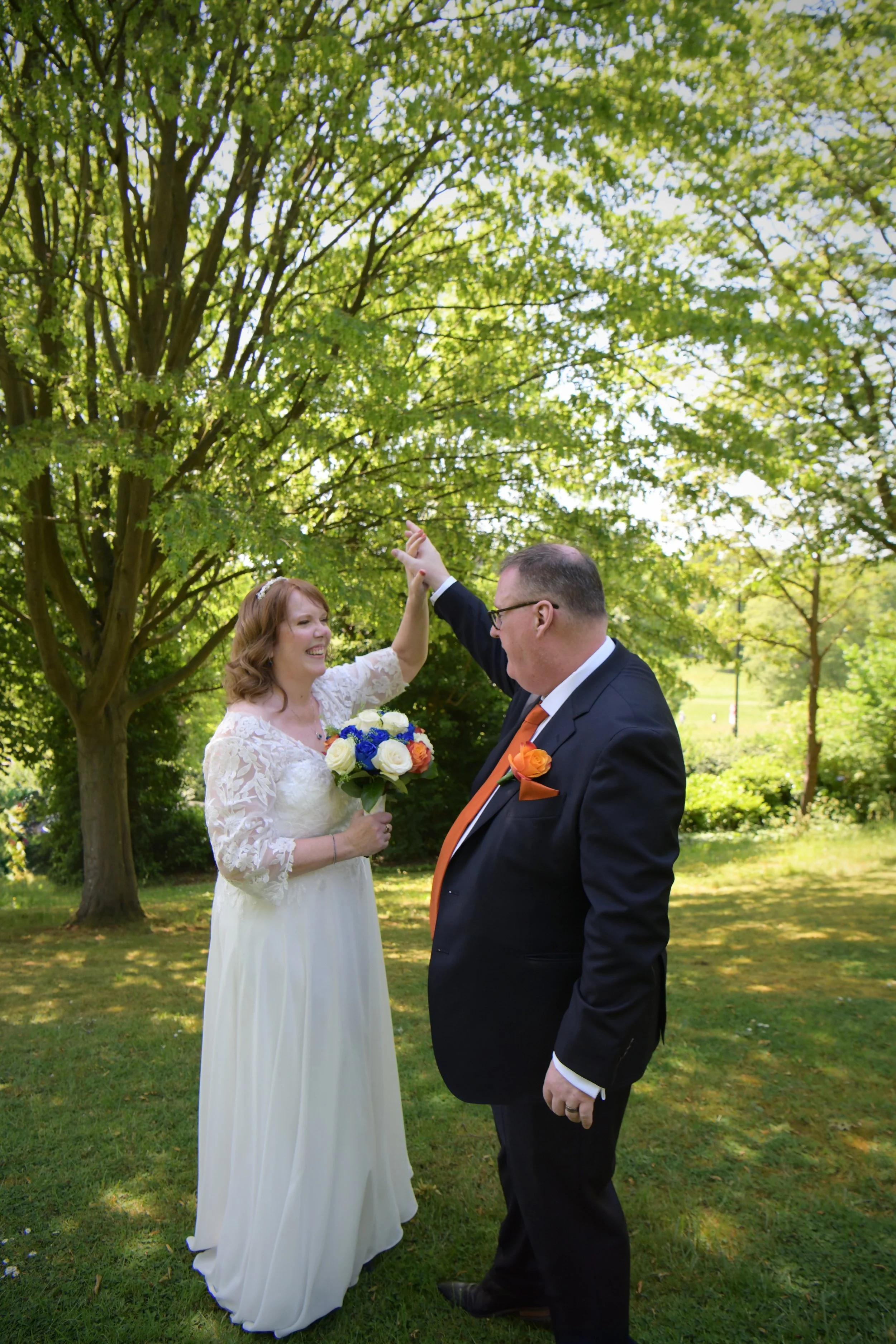 Newly married couple sharing a joyful twirl in a sunlit garden, photographed by a London wedding photographer specialising in natural and relaxed wedding photography.
