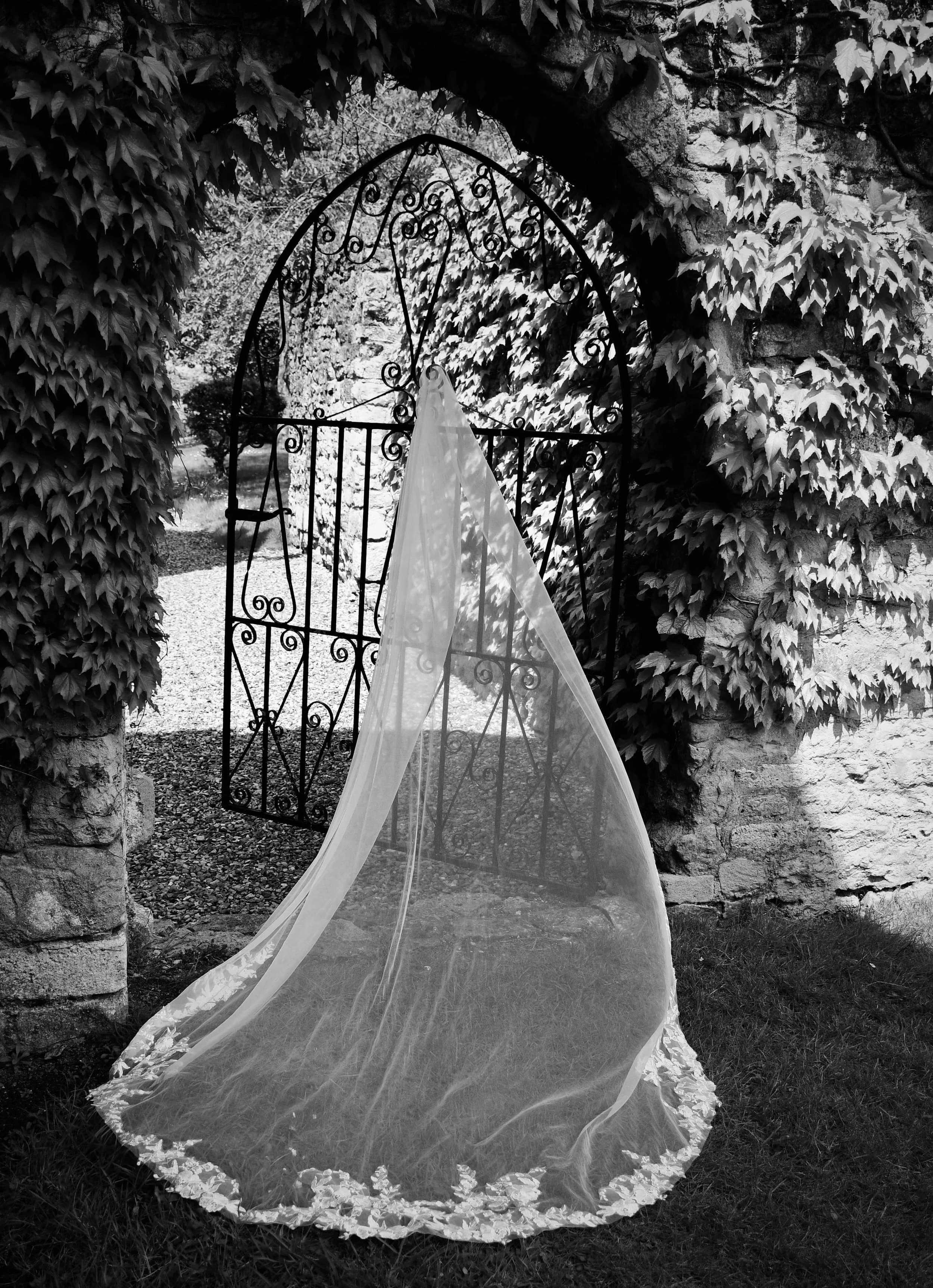 Artistic black and white wedding photography capturing a delicate bridal veil draped on an iron gate in a romantic garden setting. Shot by a London-based wedding photographer known for authentic, creative, and joyful storytelling.
Keywords: London we