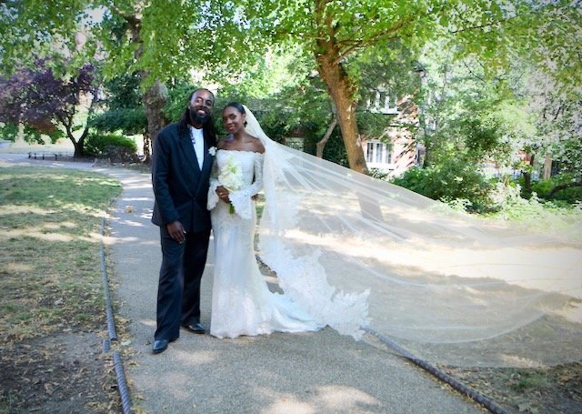 Bride and groom posing in a beautiful garden in Angel, London, on their wedding day, with the bride holding a white floral bouque