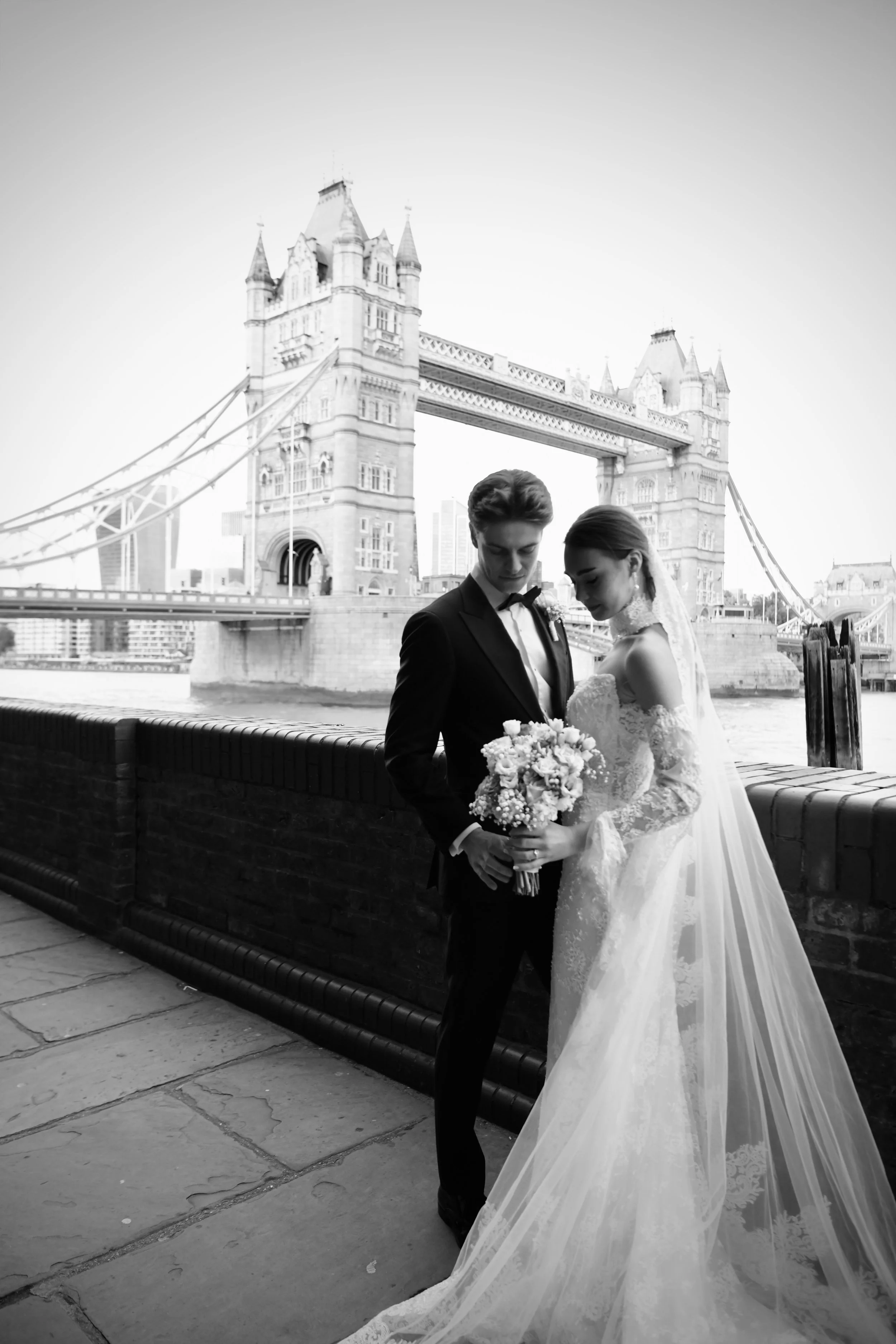A romantic black and white wedding portrait of the bride and groom sharing an intimate moment by Tower Bridge, London 