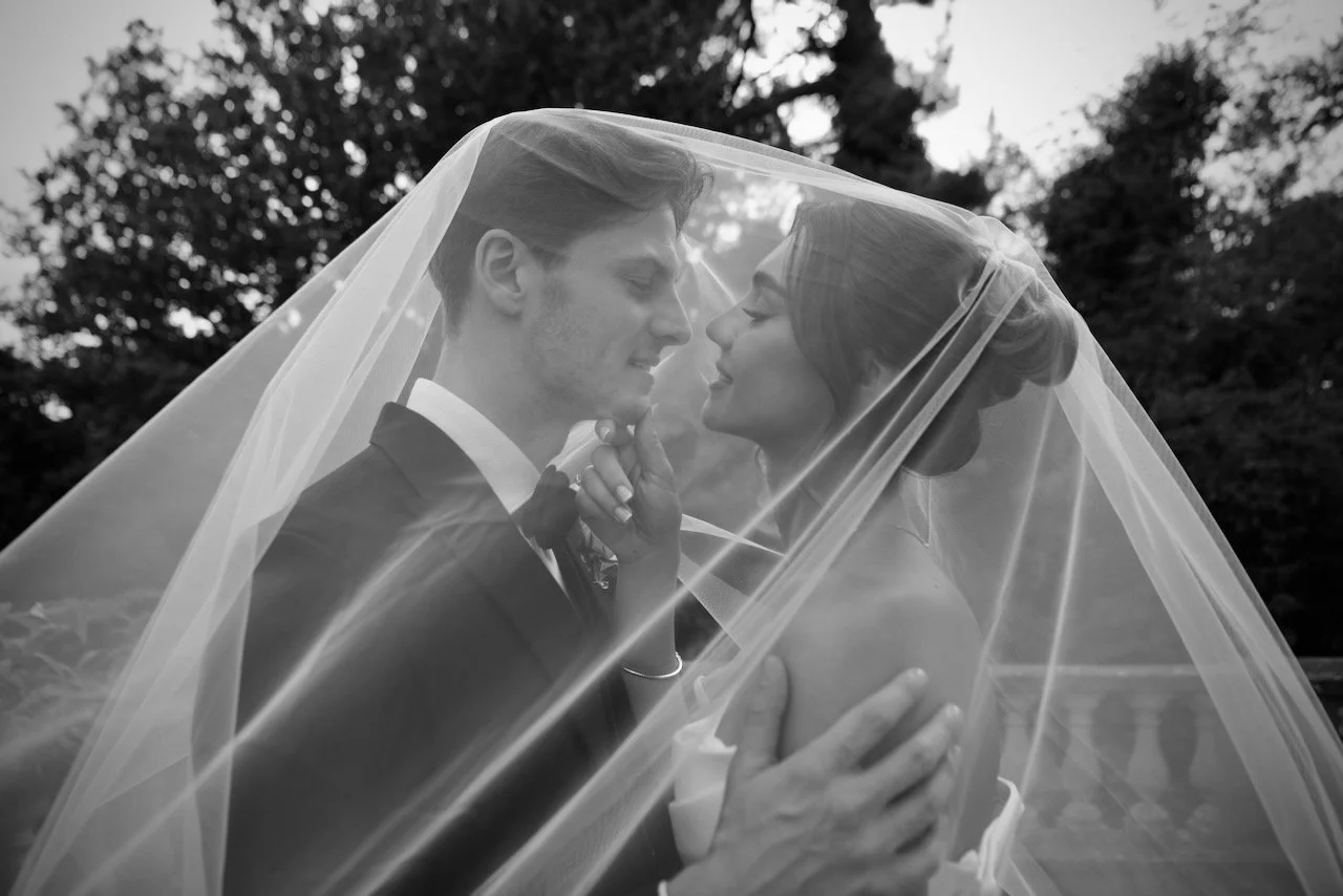 Bride and groom smiling at each other under the veil