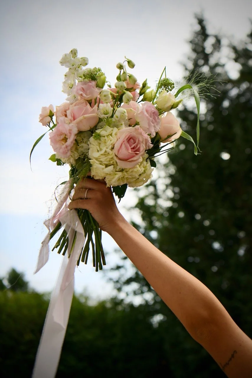 Bride holding her colourful bouquet up in the air