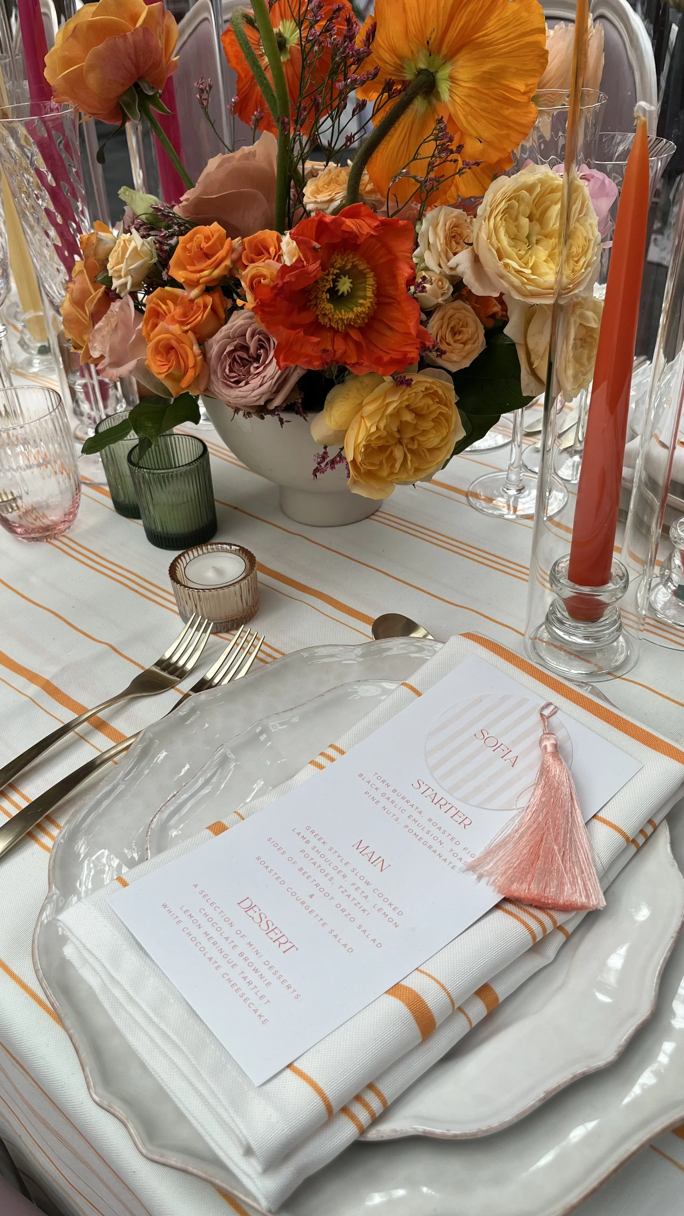 Elegant wedding table styling with vibrant orange floral centerpiece, soft candlelight, and refined place setting details—perfect inspiration for luxury, romantic wedding receptions and modern bridal design.