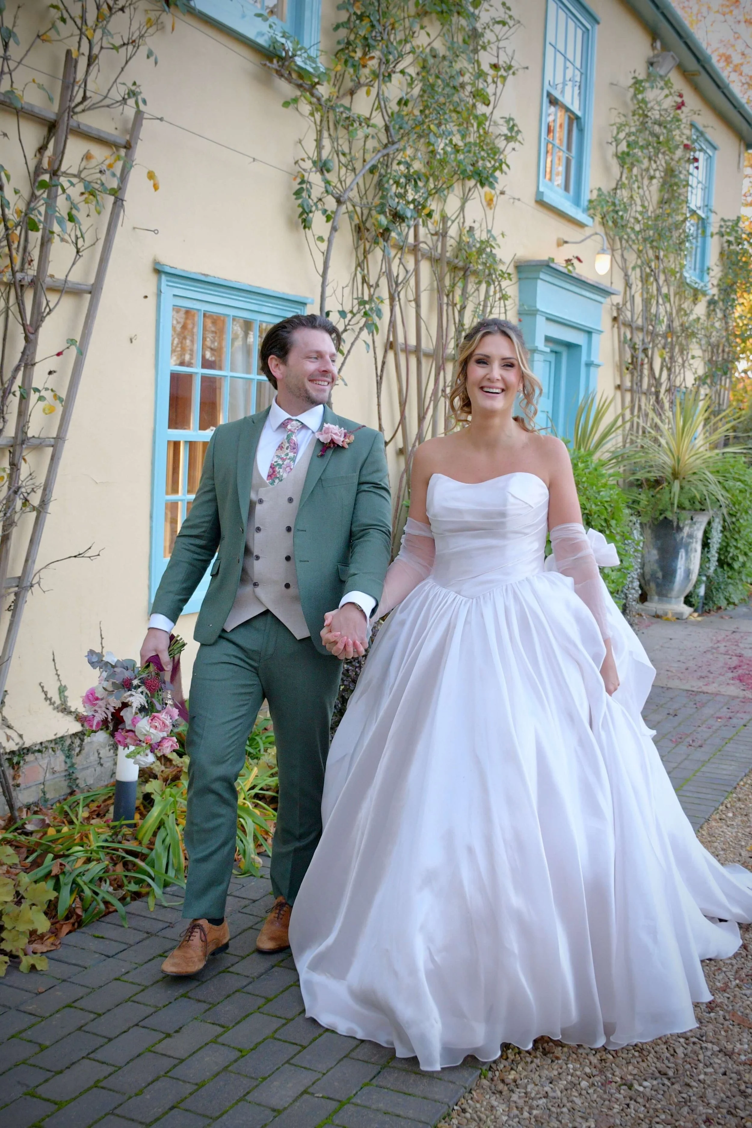 Bride and groom walking hand-in-hand outside
