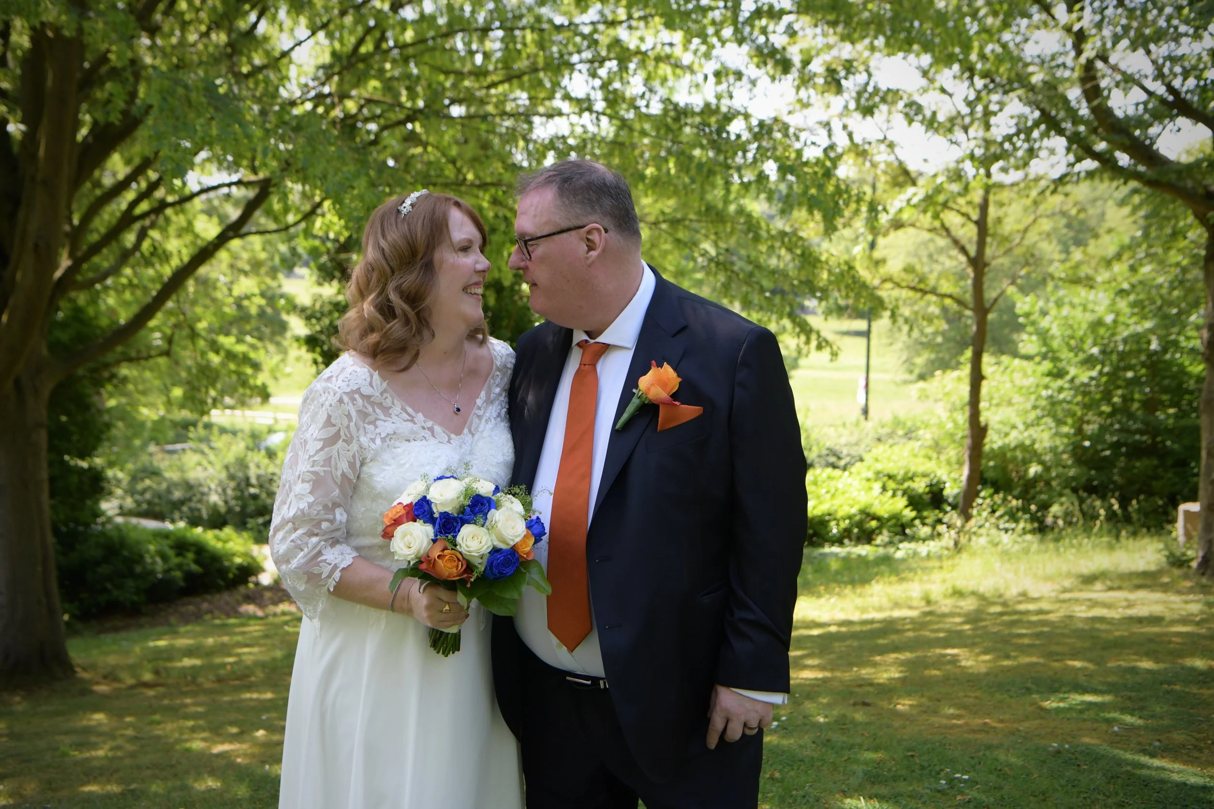 Newly married couple in a sunlit garden, photographed by a London wedding photographer specialising in natural and relaxed wedding photography.