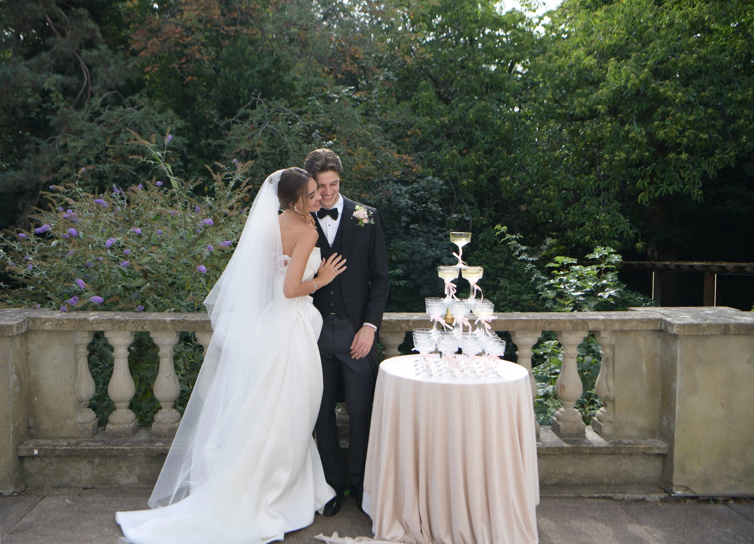 London wedding photographer capturing newlyweds embracing beside a champagne tower in a beautiful garden 