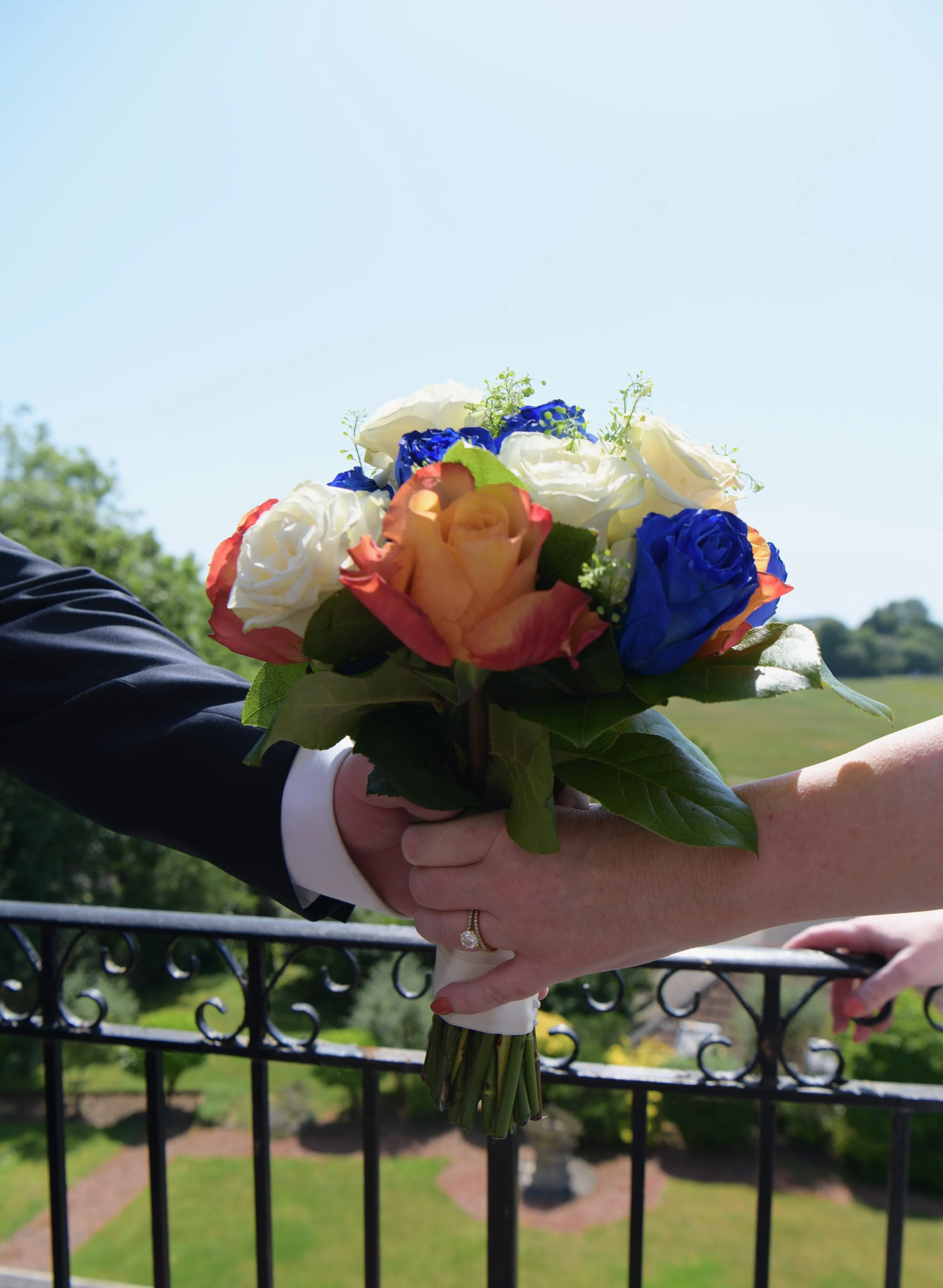 Close-up of a colourful bridal bouquet held by the newlyweds overlooking beautiful countryside views, photographed by a London wedding photographer.
