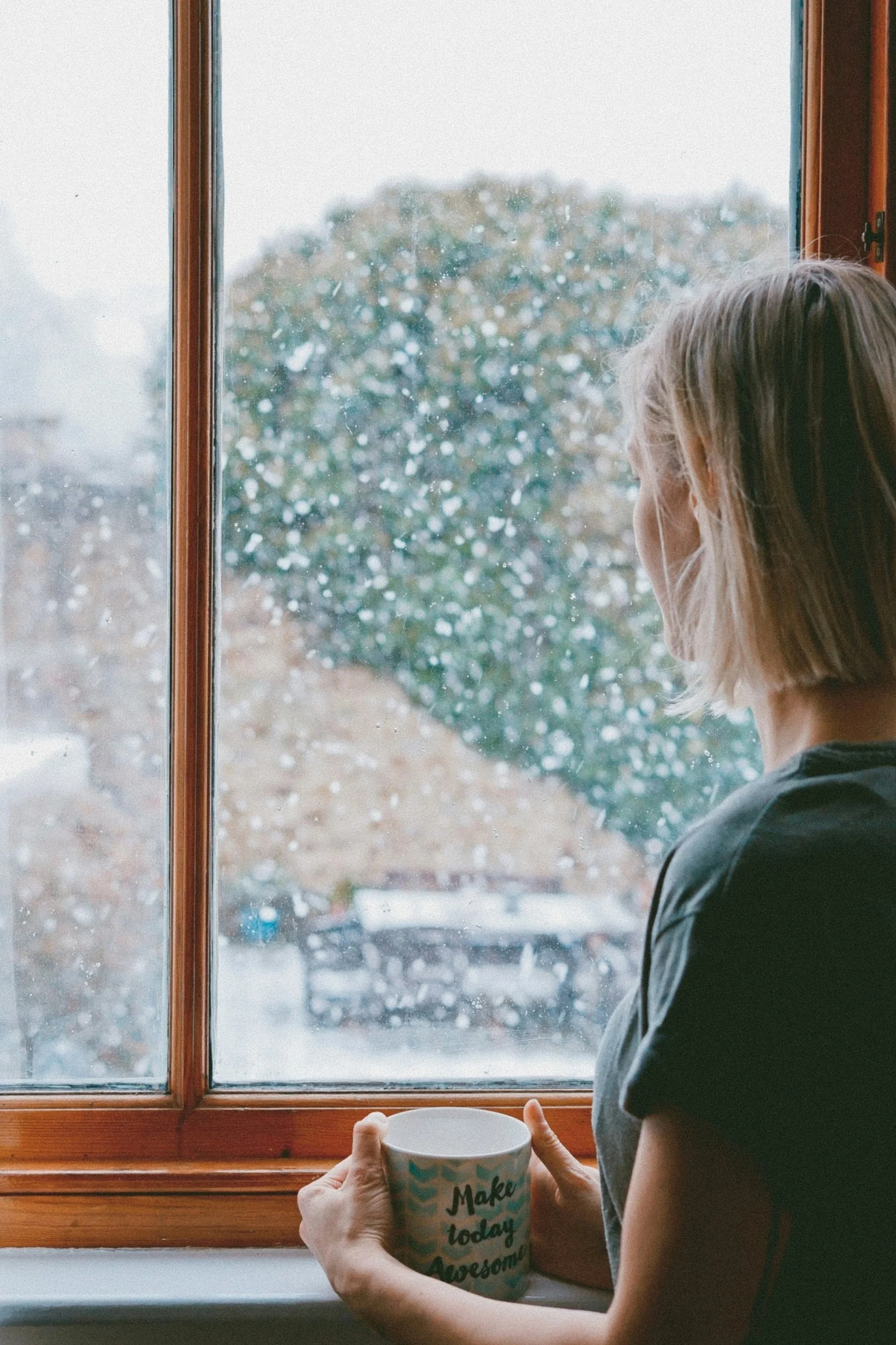 Woman looking out window — feeling guilty for resting while others are still struggling, a sign of burnout