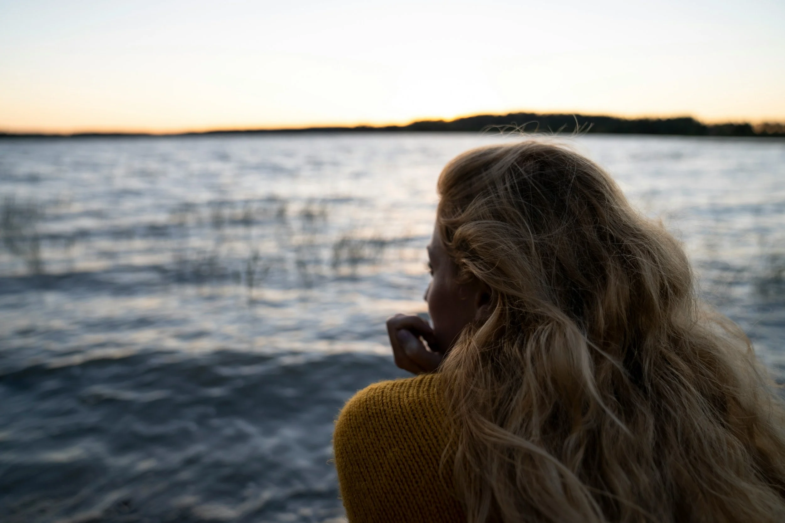 Woman looking out at a lake reflecting on over-functioning, burnout, and emotional exhaustion