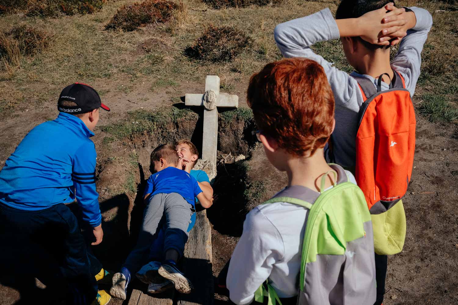 The kids from Peñaranda’s Diego Marin school take turns throwing themselves into an open grave.