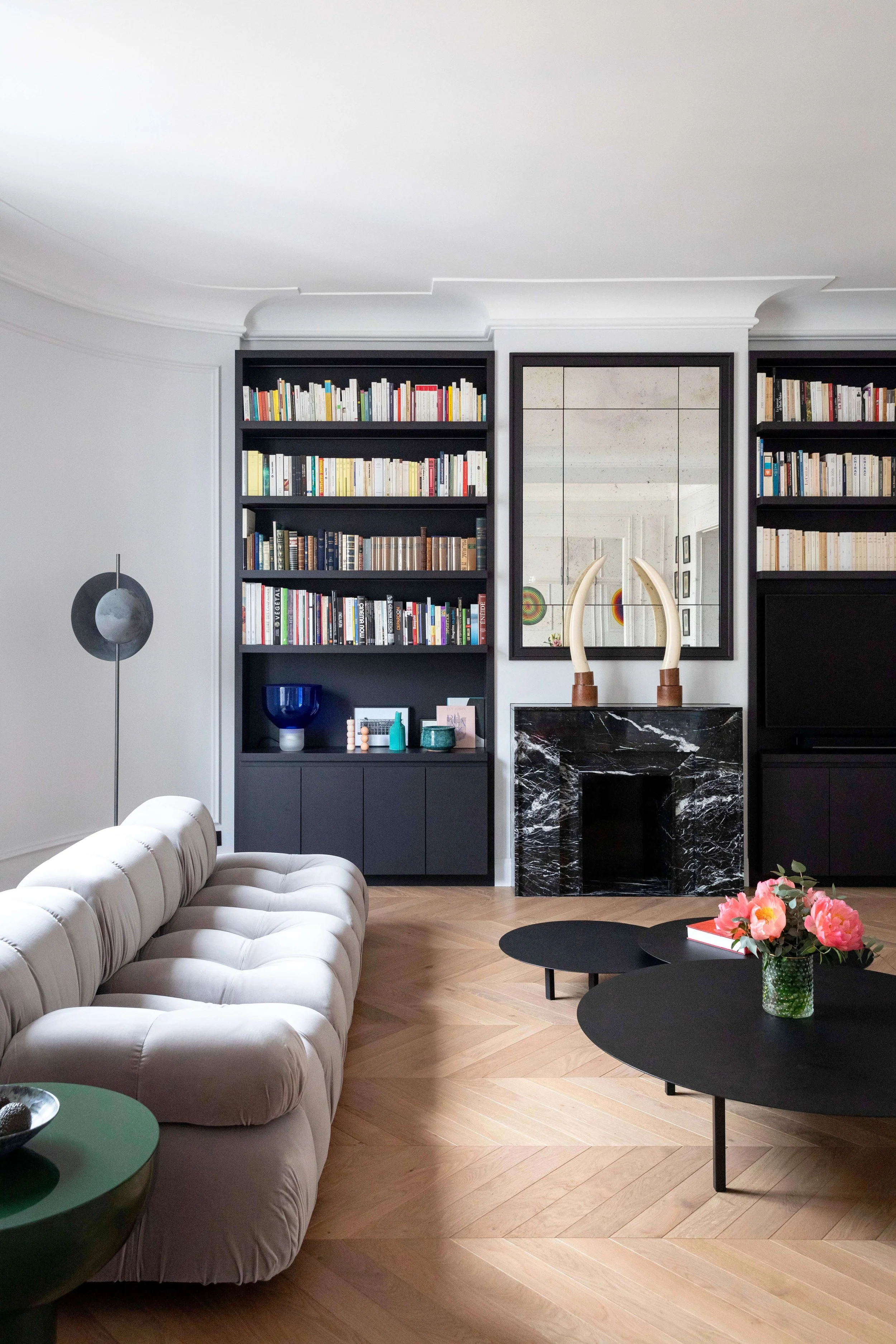 Cheminée en marbre noir et bibliothèque sur mesure dans le salon d’un appartement haussmannien à Paris 16