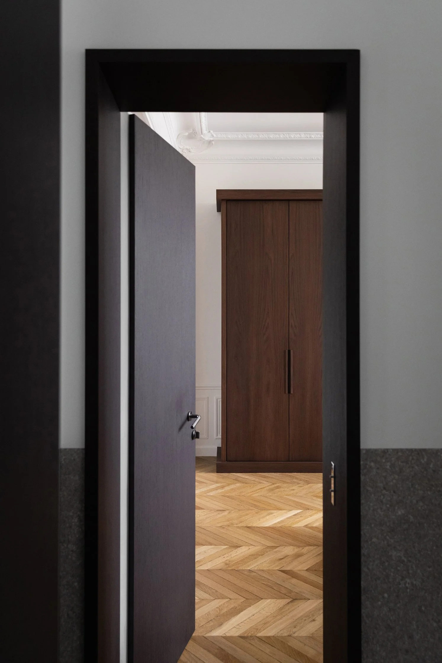 Porte en bois sombre ouvrant sur un dressing Obumex sur mesure dans un appartement haussmannien rénové