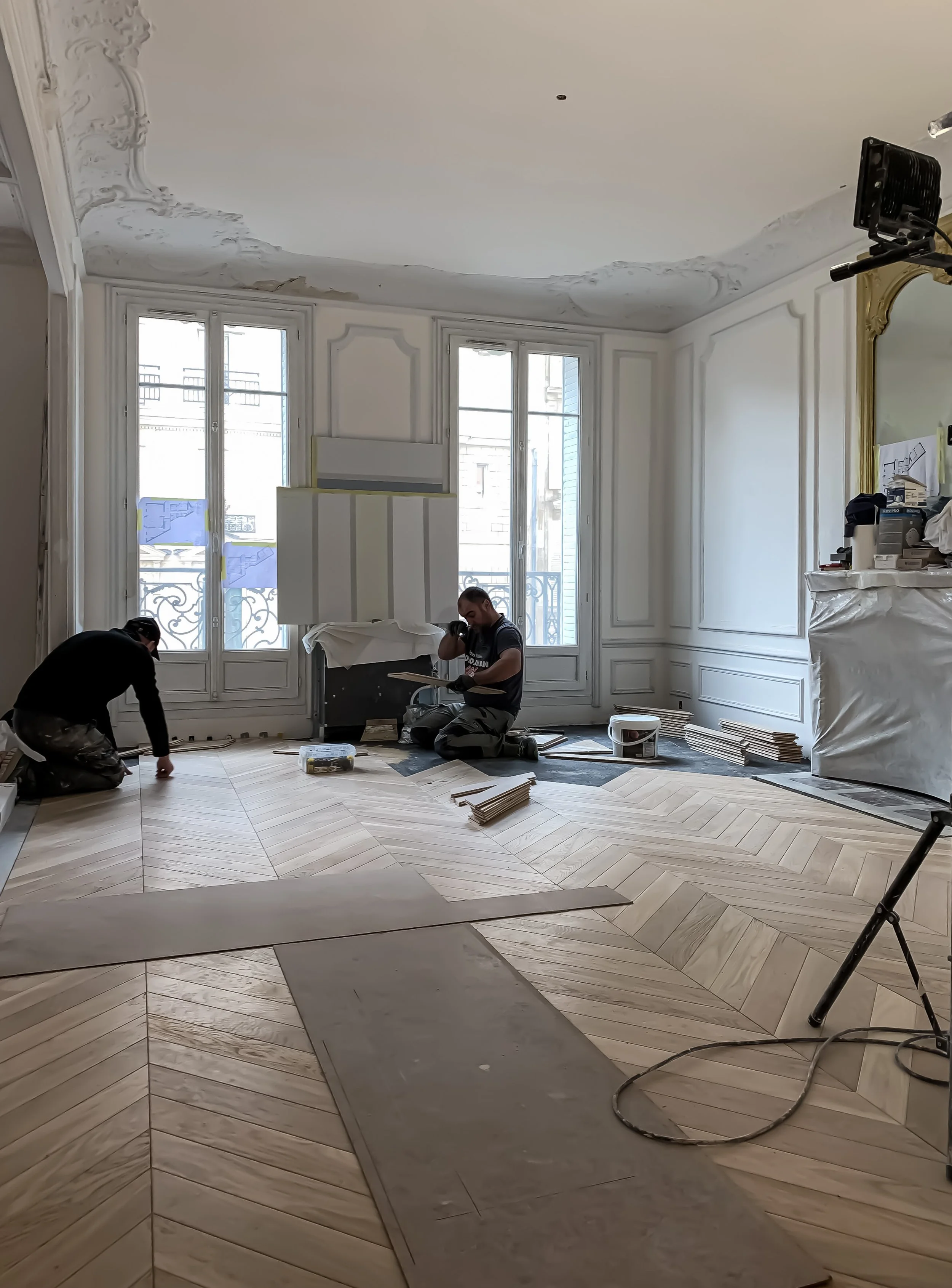 Les ouvriers posent le parquet en point de Hongrie dans le salon d'un appartement haussmannien à Paris