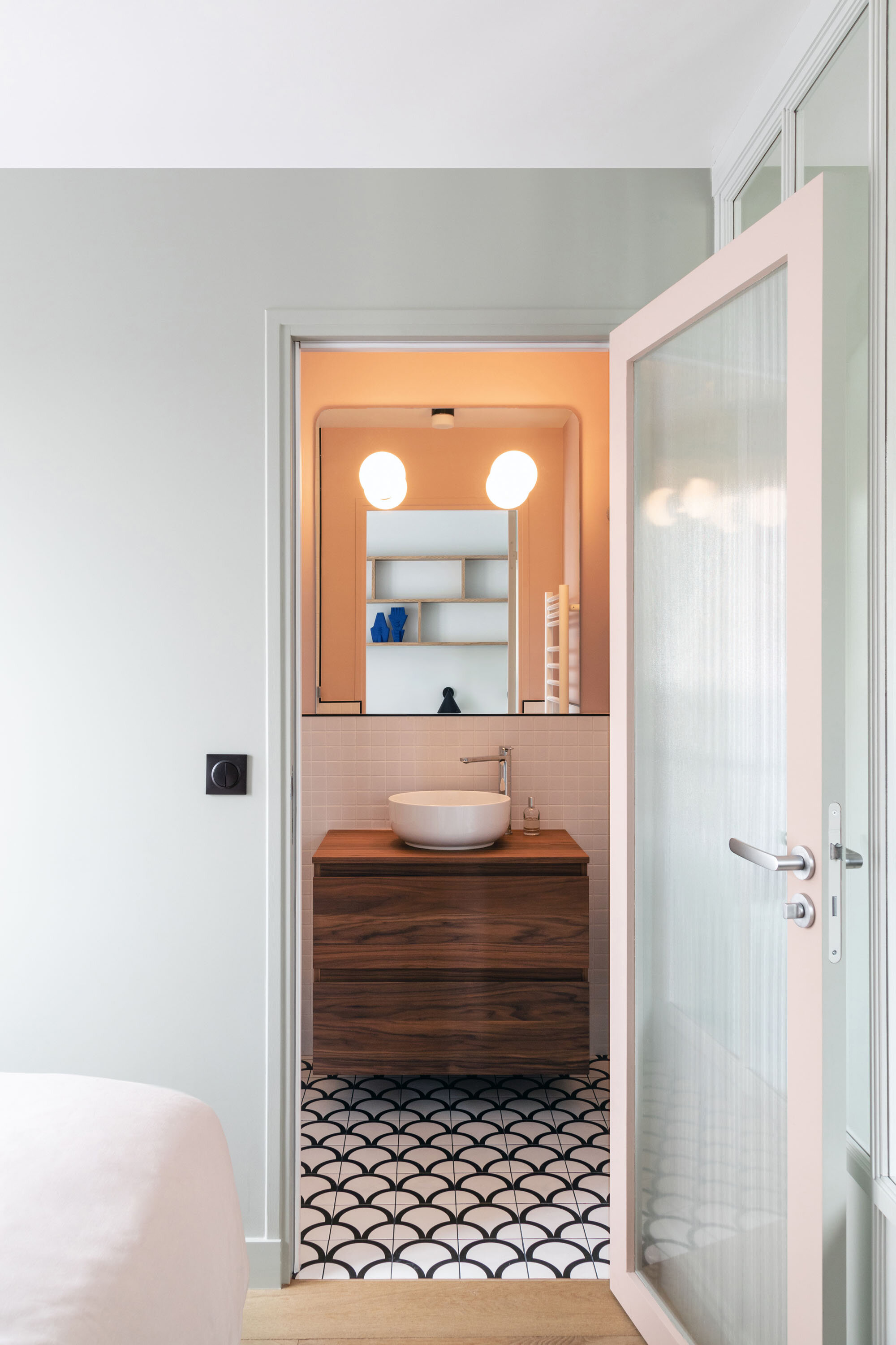 Une porte vitrée sépare la chambre de la salle de bain rose