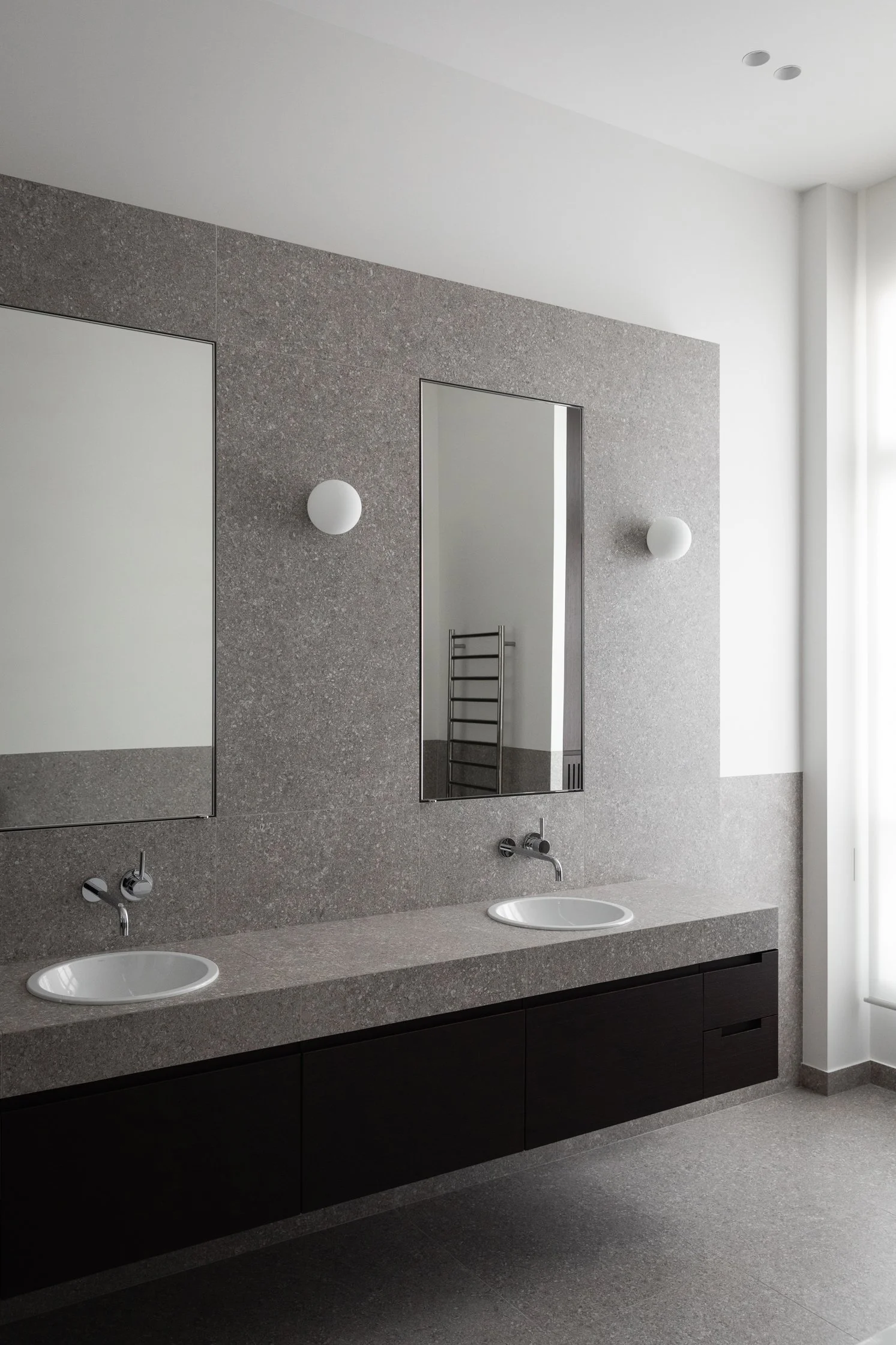 Salle de bain avec double vasque, meuble sur mesure en bois sombre et parement en gré cérame effet pierre à Paris 16