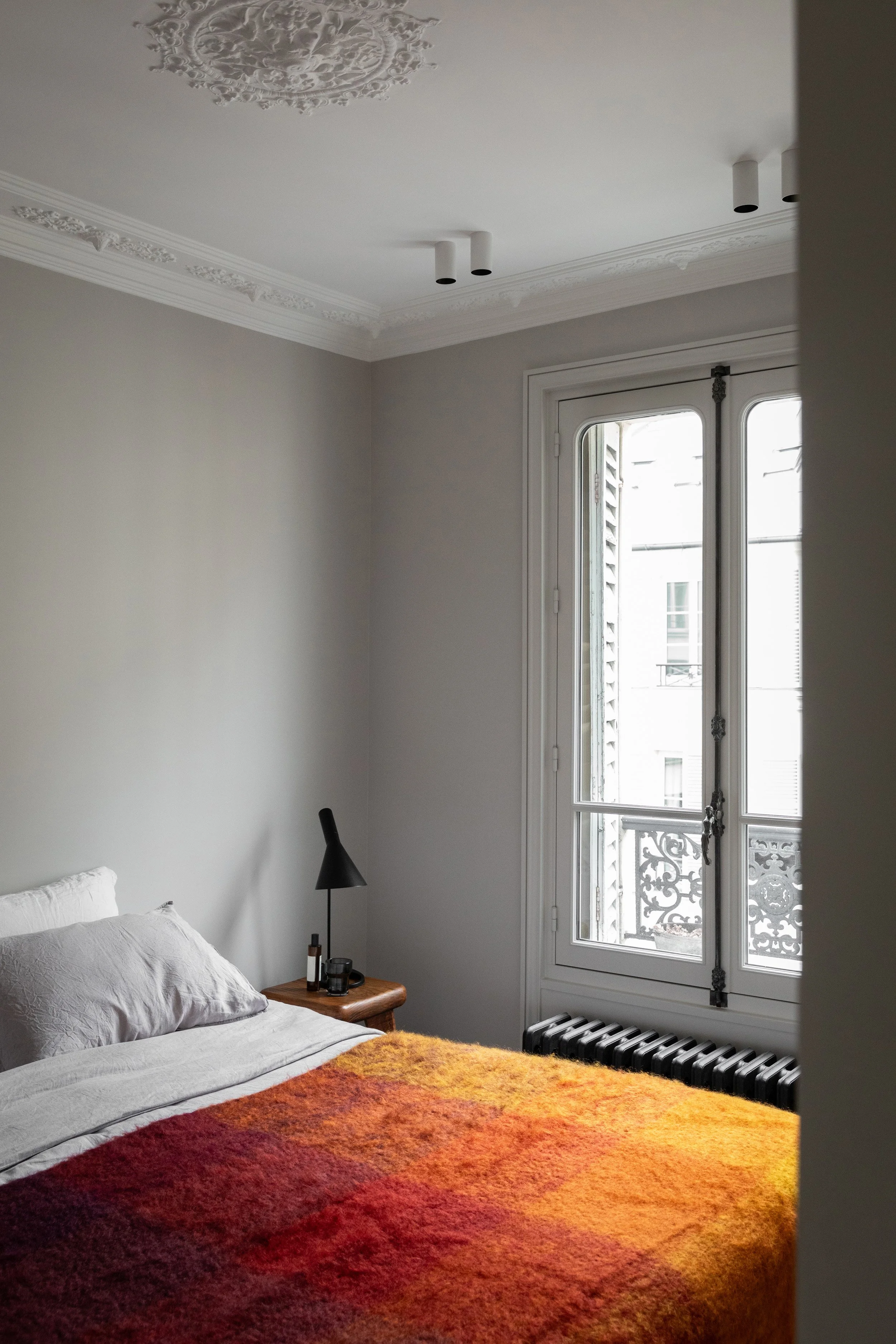 Chambre d’un appartement rénové dans le Marais à Paris 3 avec moulures et fenêtre ancienne