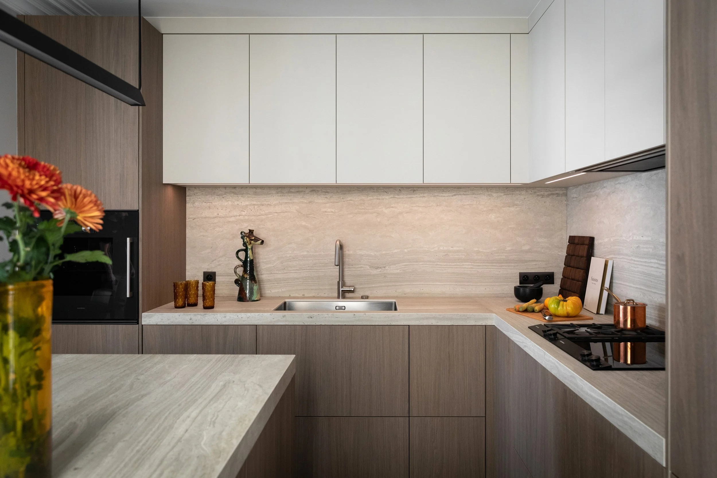 Détail de la cuisine et son îlot en bois avec plan de travail en céramique effet pierre dans un appartement rénové à Paris 3