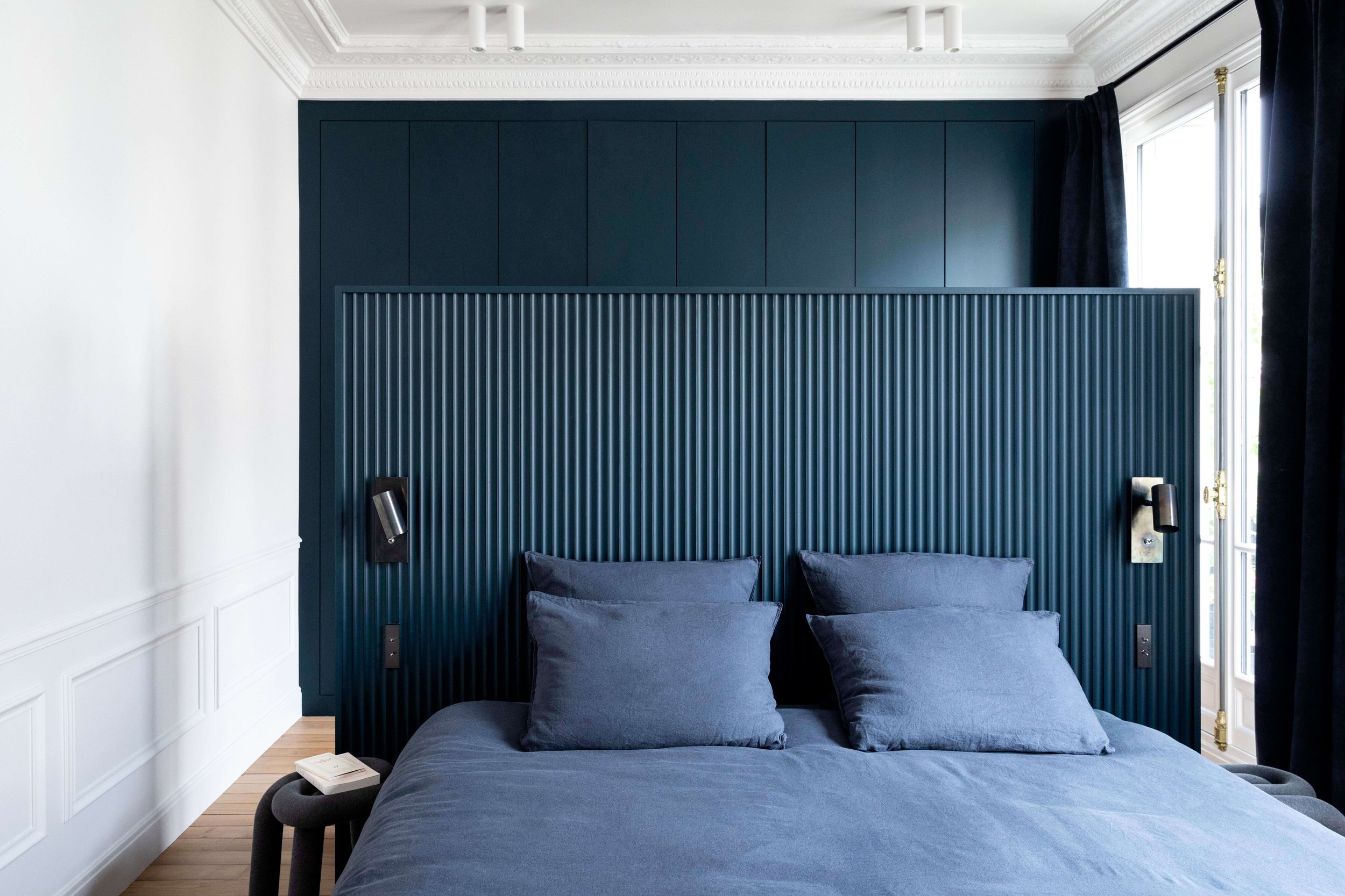 Chambre aux tons bleu profond dans un appartement haussmannien rénové à Paris 16 avec moulures restaurées
