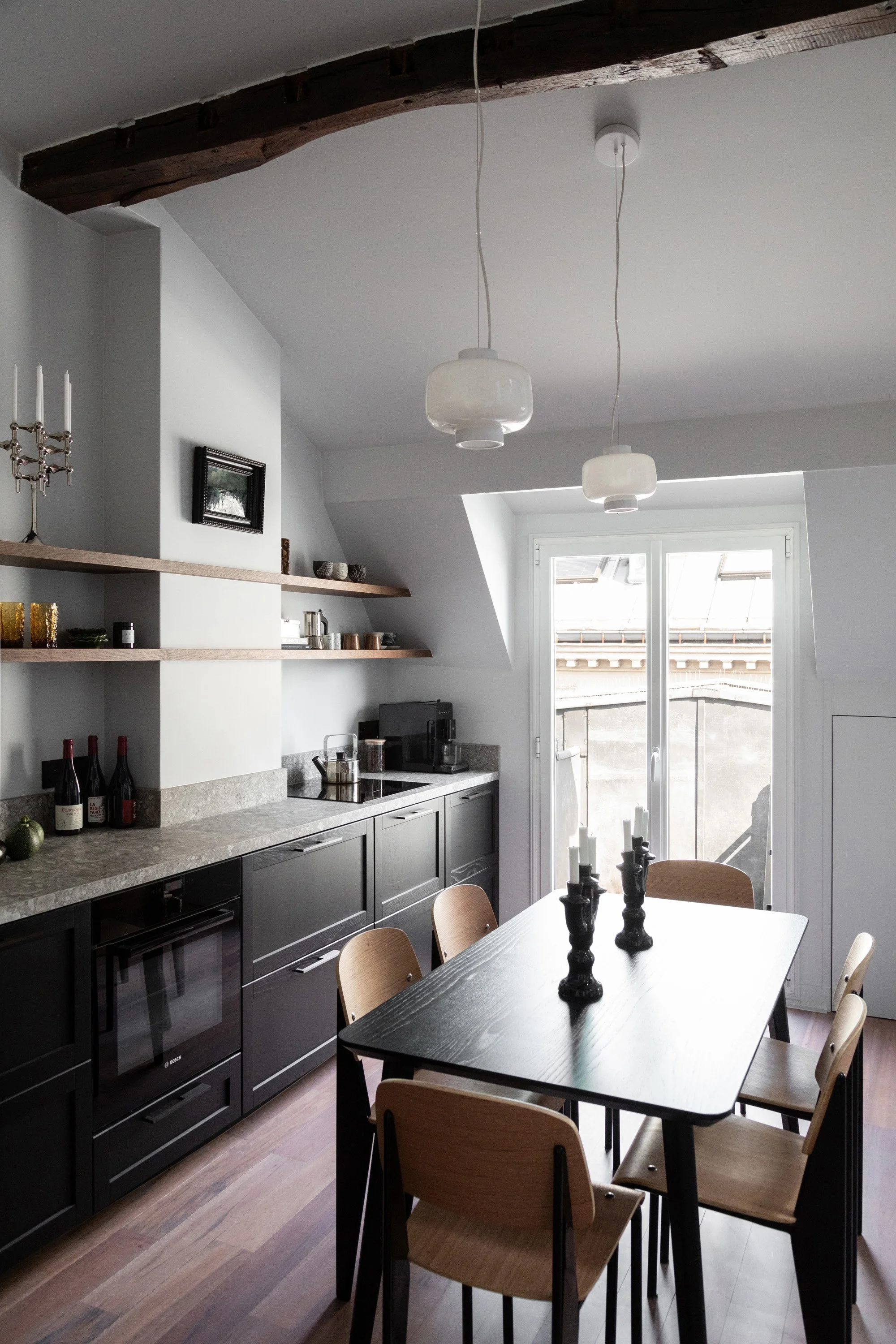 Cuisine noire et salle à manger sous les toits d’un appartement rénové à Paris 9