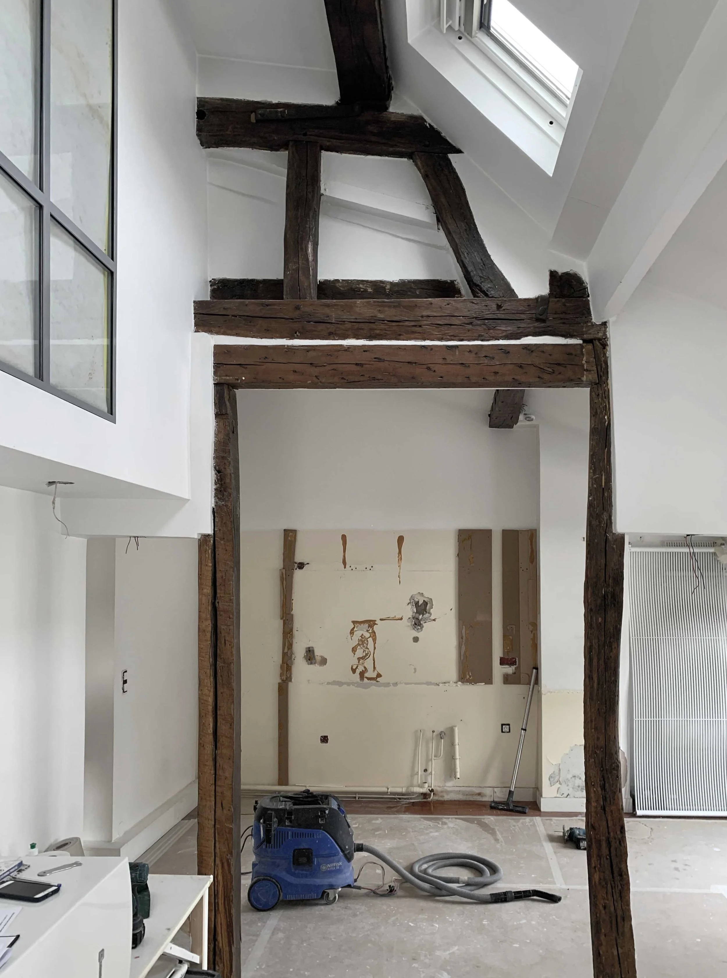 Chantier de rénovation révélant les poutres anciennes d’un appartement à Paris 9