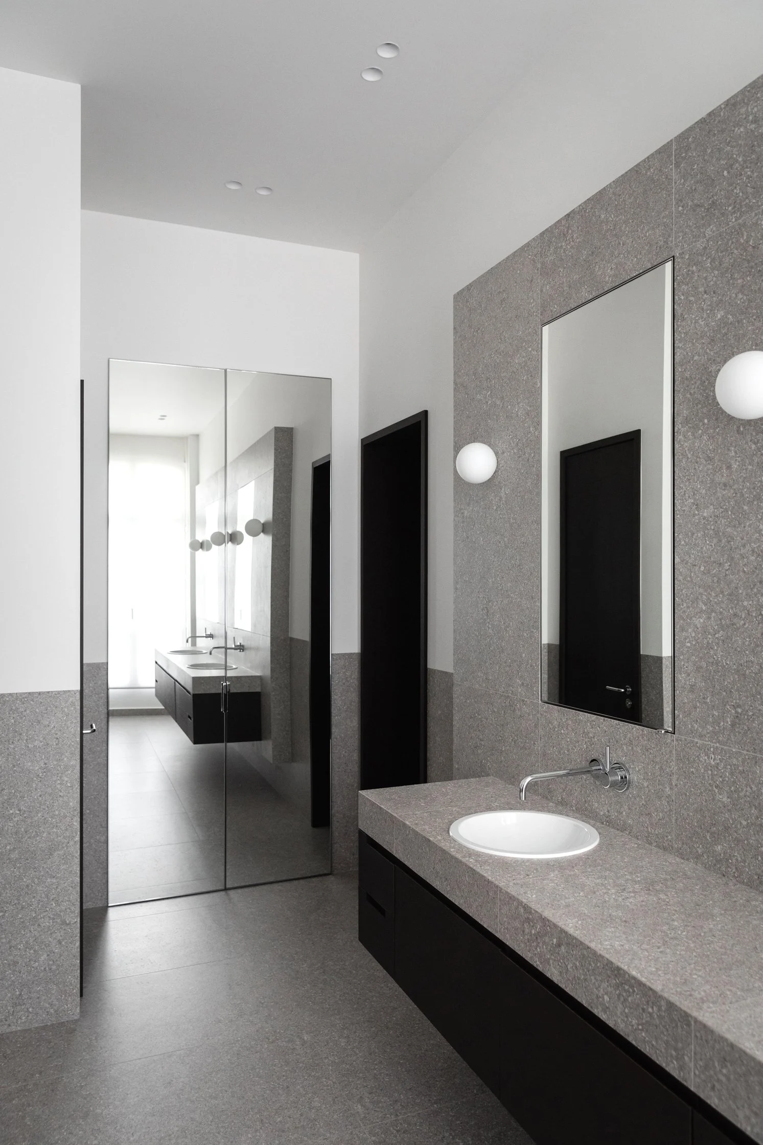 Salle de bain en gré cérame grise et bois sombre avec meuble vasque sur mesure dans un appartement rénové à Paris 16