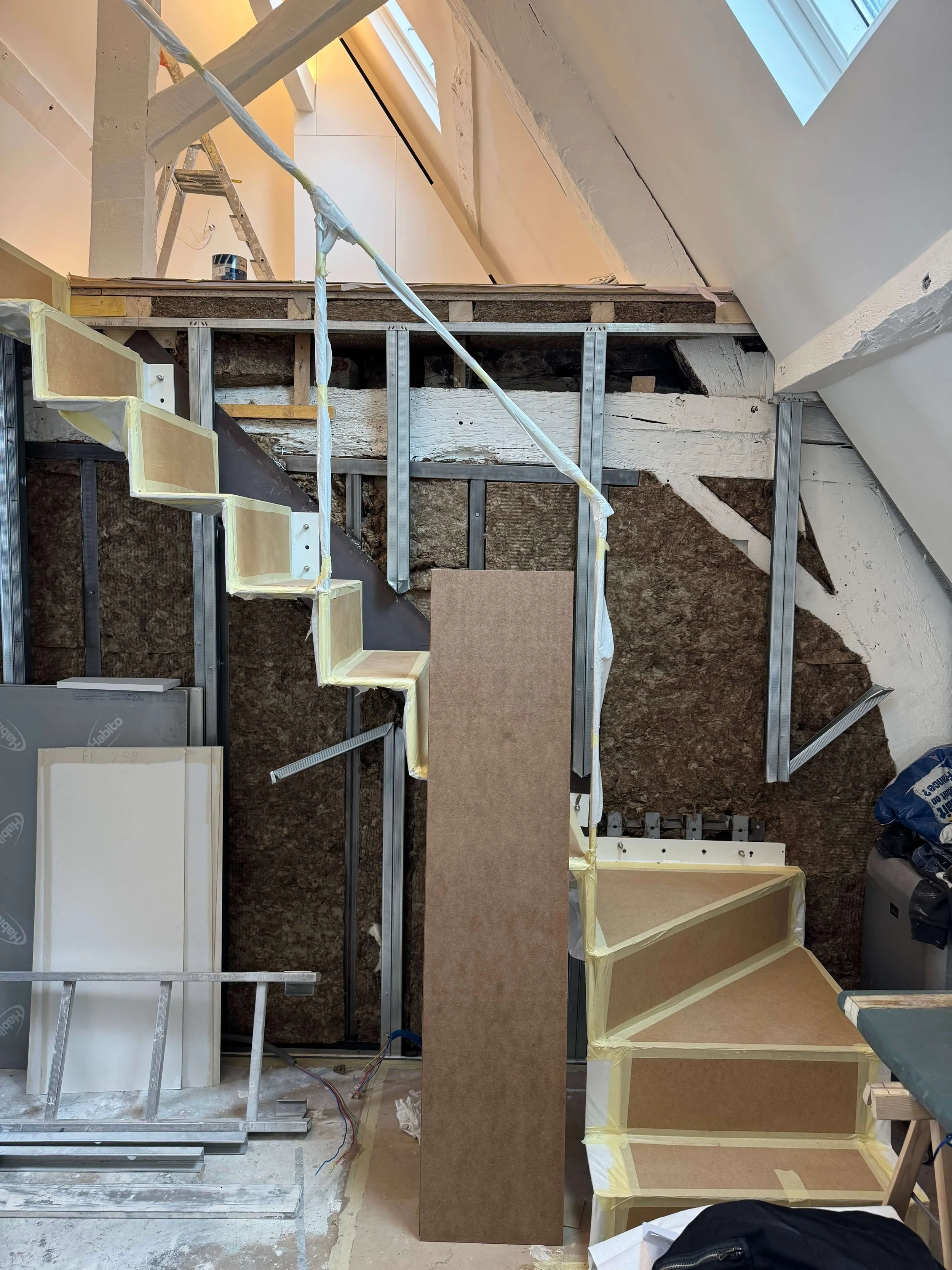 Mise en oeuvre d'un escalier en acier en porte à faux dans le séjour d'un appartement sous les toits dans le Marais