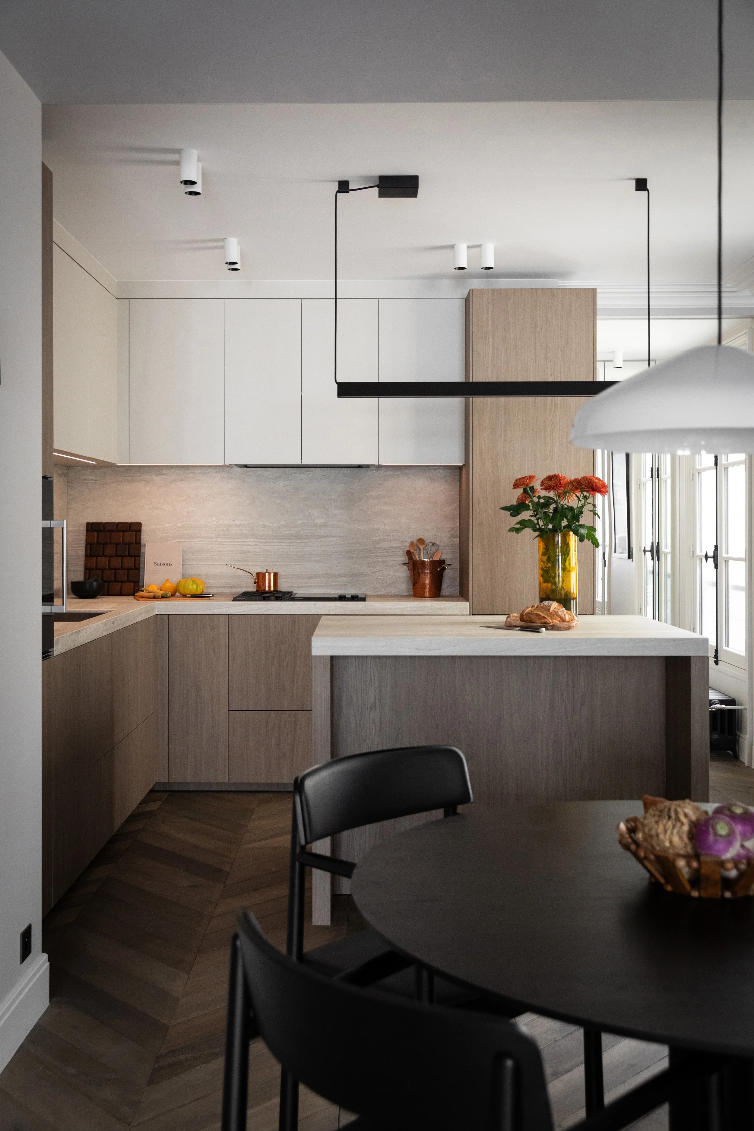 Cuisine ouverte sur la salle à manger et son îlot dans un appartement rénové du Marais à Paris 3